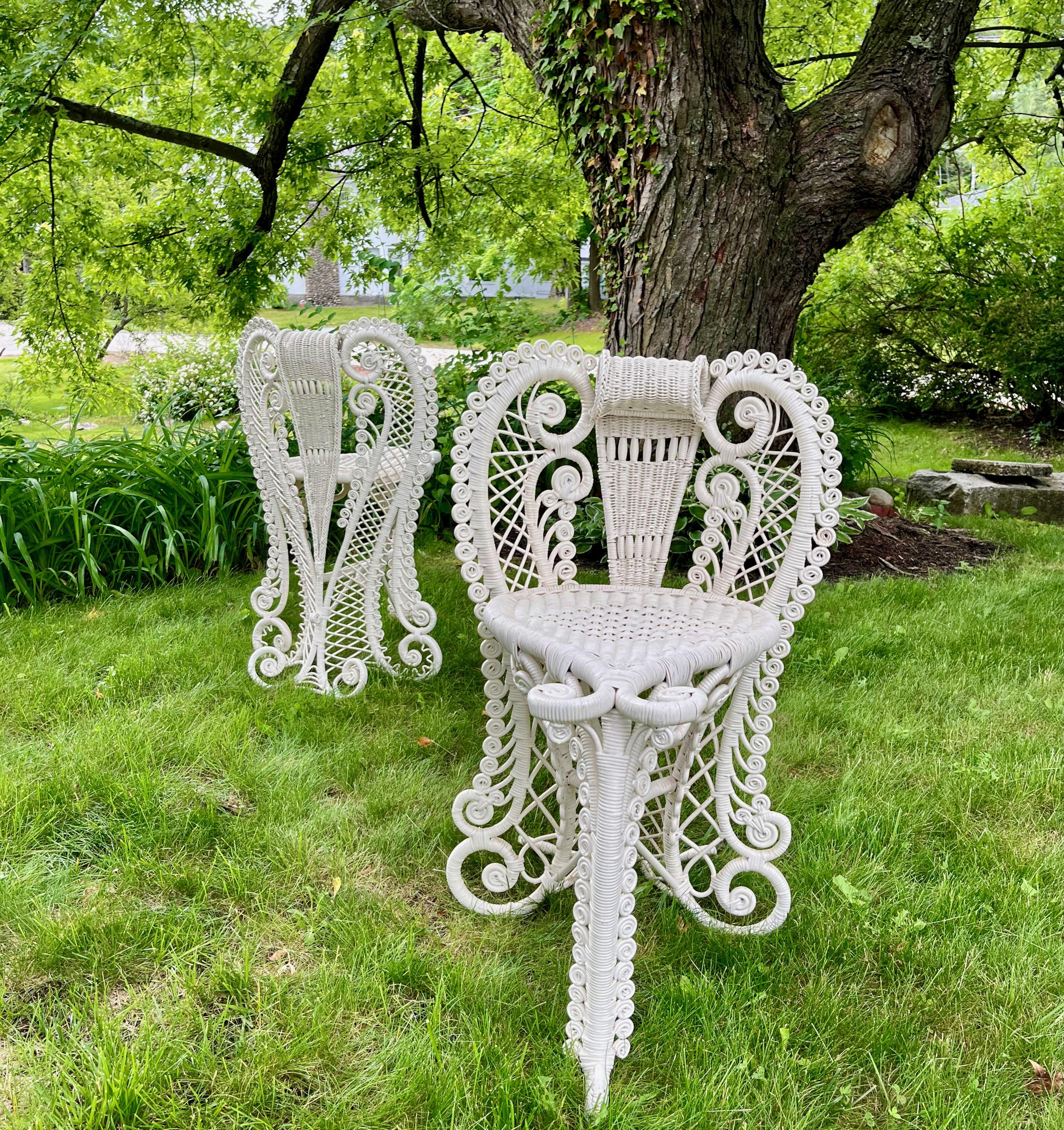 A pair of very unique and very rare white painted Heywood Brothers and Wakefield Company posing chairs, Circa 1898, designed with elephant trunk designed fronts and Aladdins feet designed backs, These chairs are highly decorative with curlicues all
