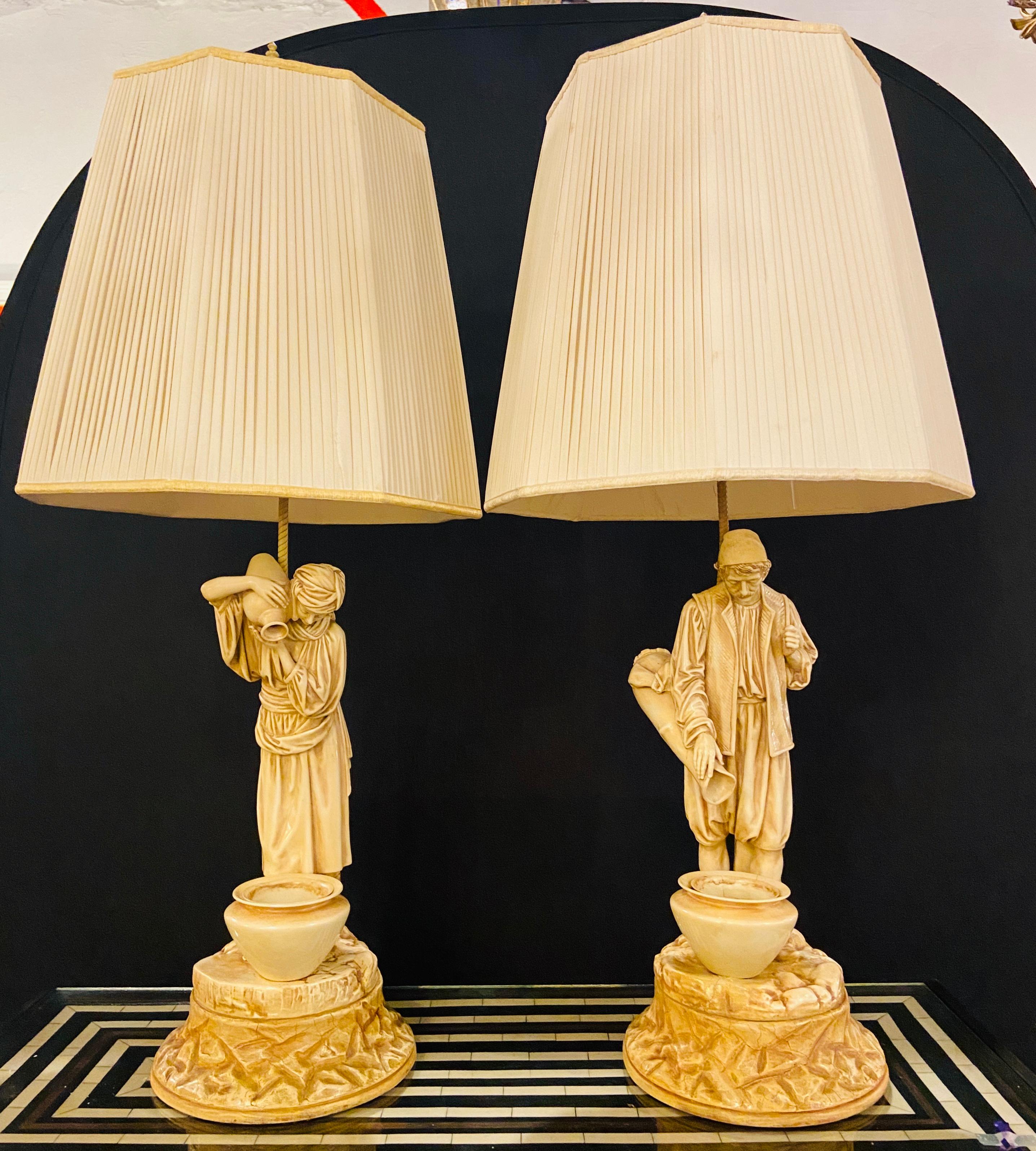 A pair of Mid-Century Water Bearers in a Finely Cast Porcelain Finish Table Lamps. This pair of water bearers of a man and woman carrying water pots features cast porcelain finish and pots with inserts. The handmade lamps are finely handcrafted and