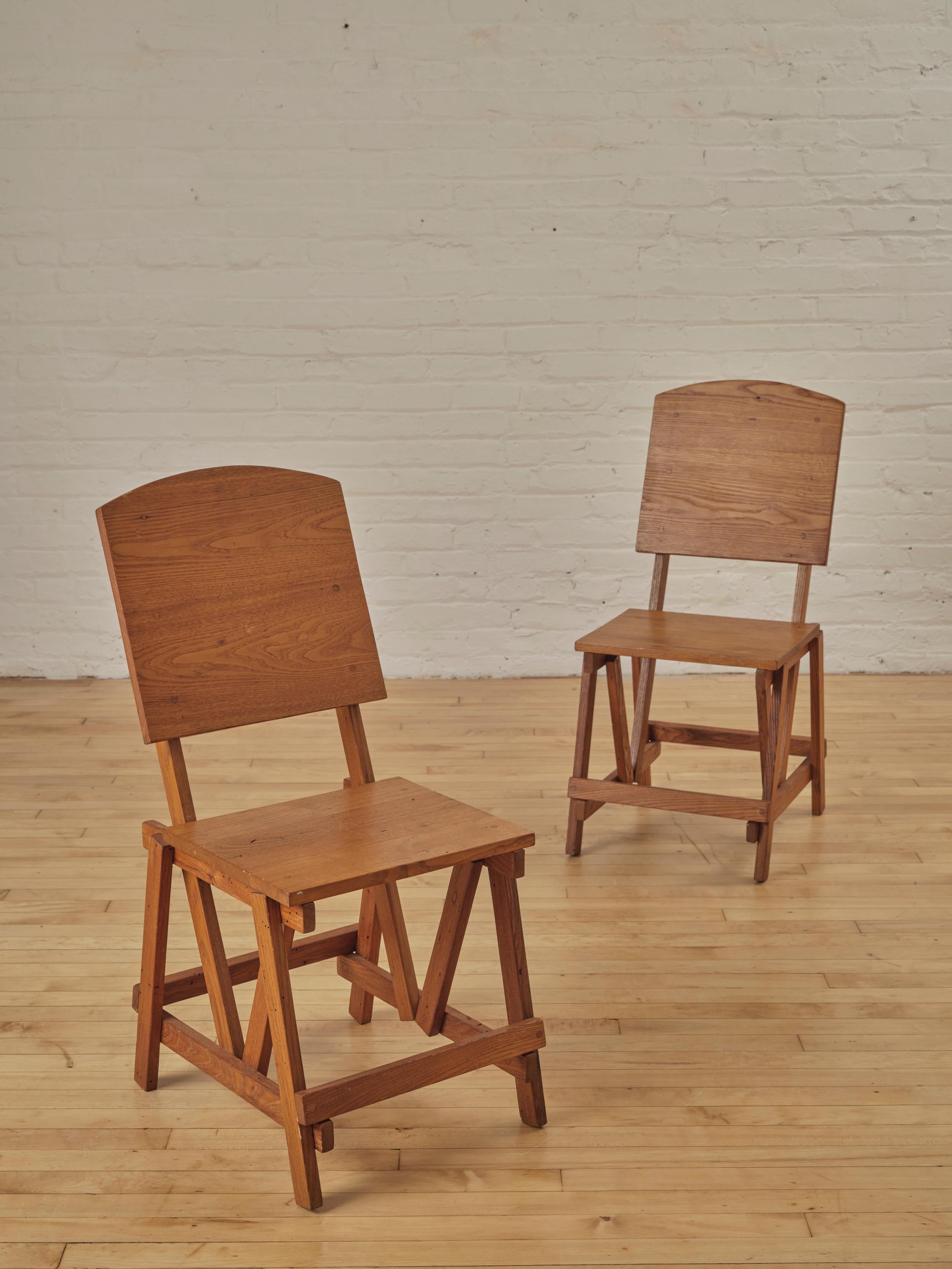 A pair of architectural constructivist oak accent chairs. These well constructed solid oak chairs feature peg joinery and architectural angels.

