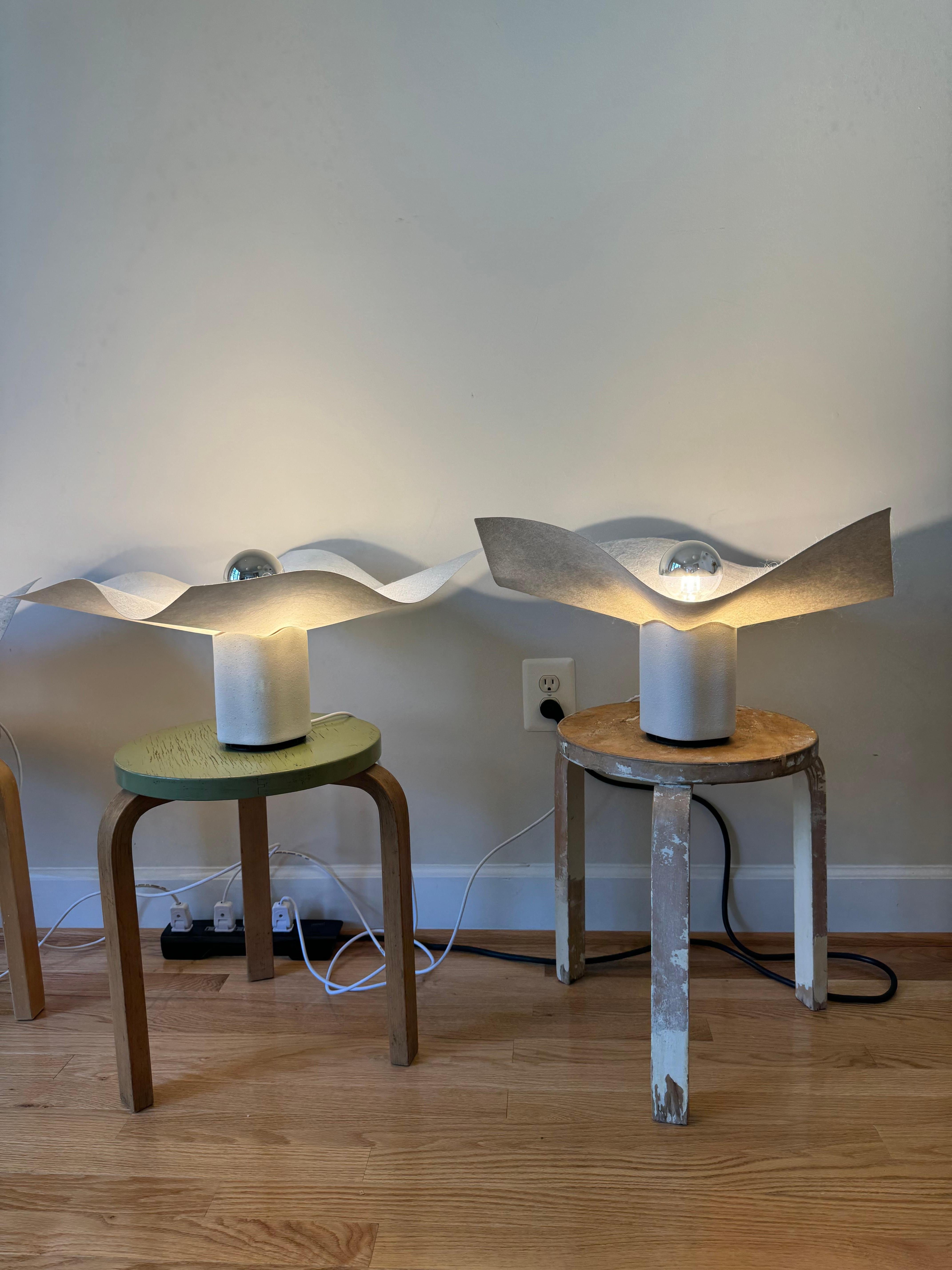 The Area 50 table lamp is part of a series of table, floor, wall and ceiling lamps designed by Mario Bellini in 1974 for Artemide. 
Bellini says he designed the lamps in relation to the immaterial nature of light, so rather than creating an object,