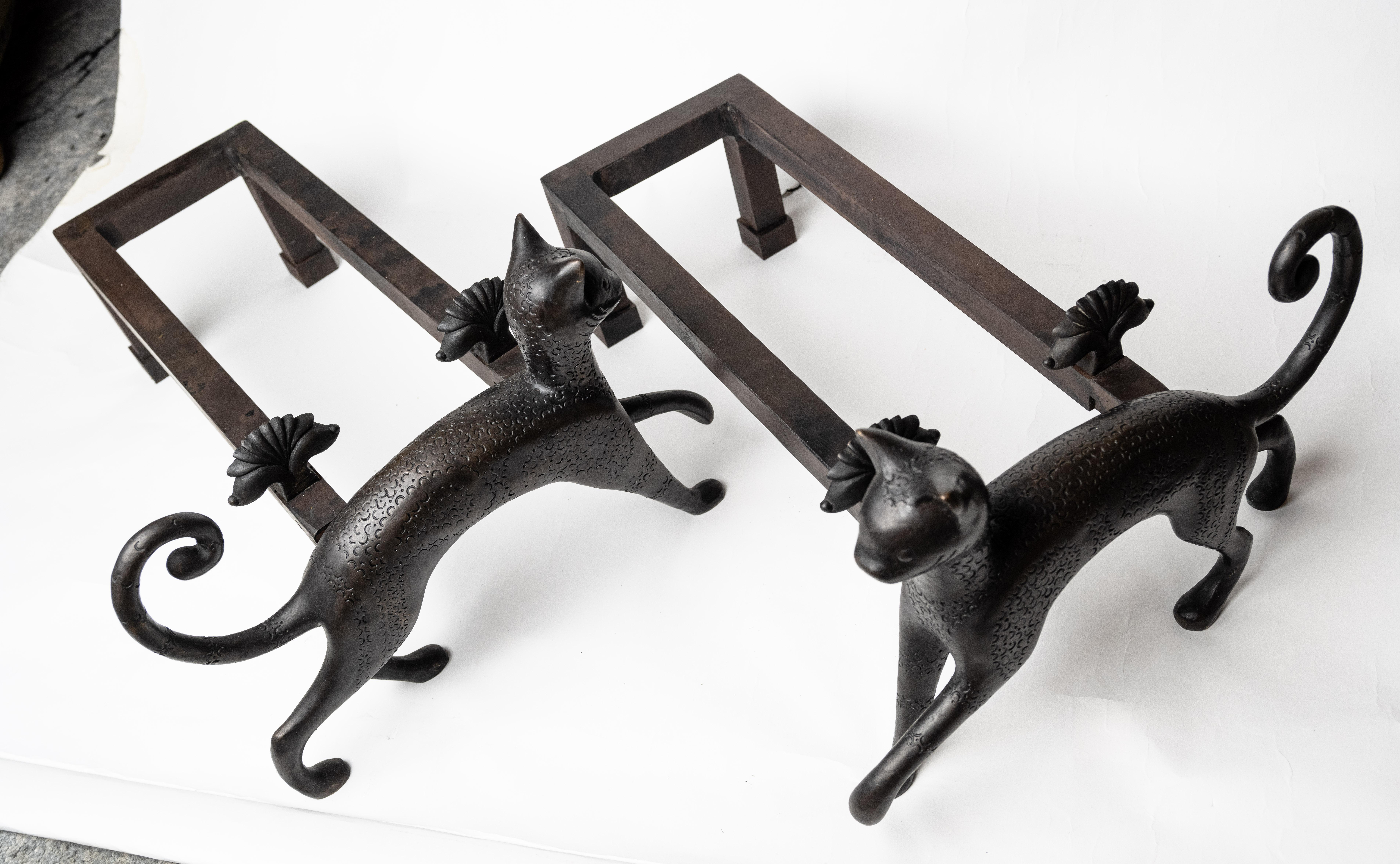A pair of Armand Rateau (1882-1938) designed andirons with symmetrical stylized felines, having arched tails and stylized heads and bodies. The figures attached to two rectangular fire boxes with decorative neoclassical rosettes. Designed in 1925.