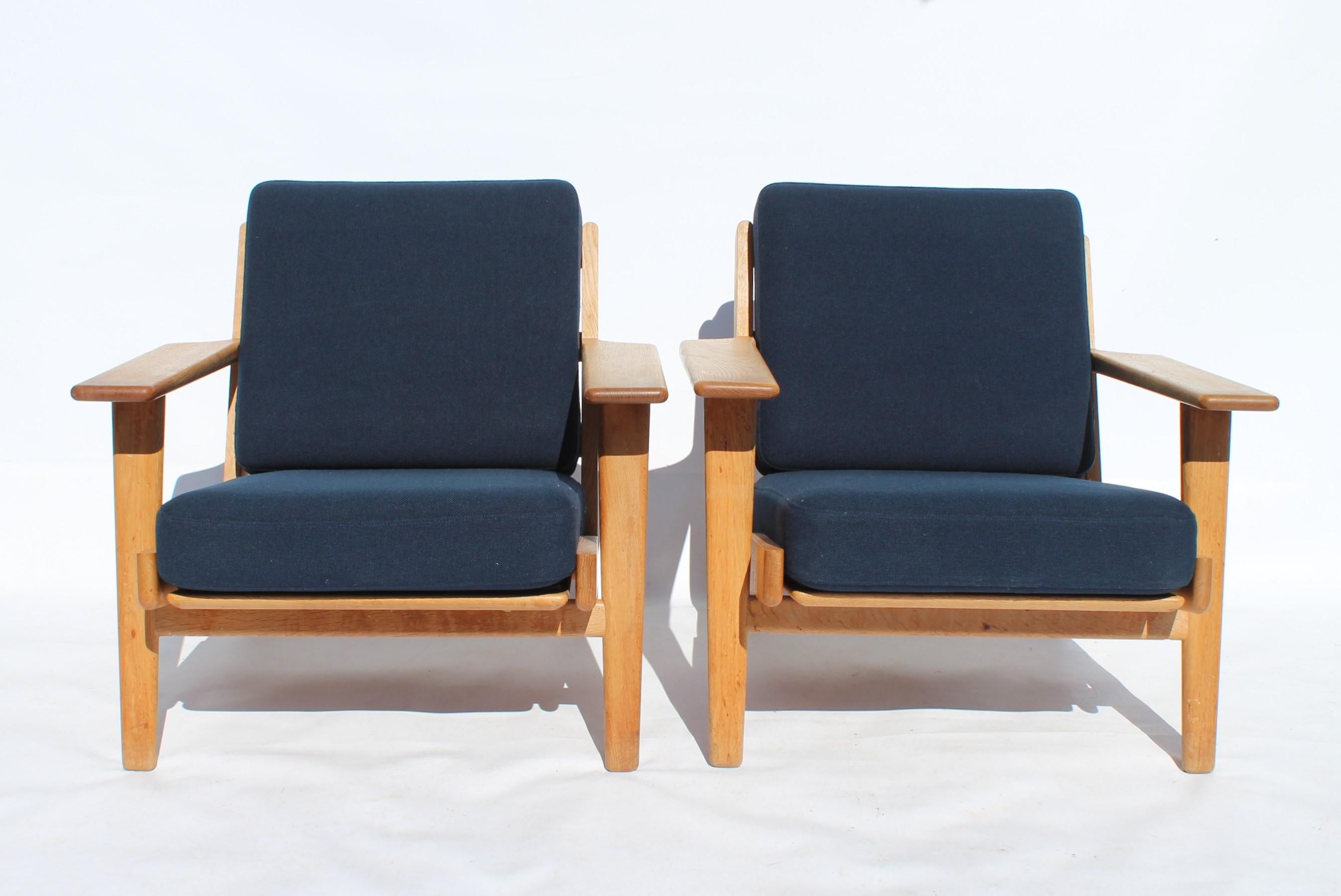 A pair of armchairs, model GE290, designed by Hans J. Wegner and manufactured by GETAMA in the 1960s. The chairs are of oak and cushions of dark blue wool.