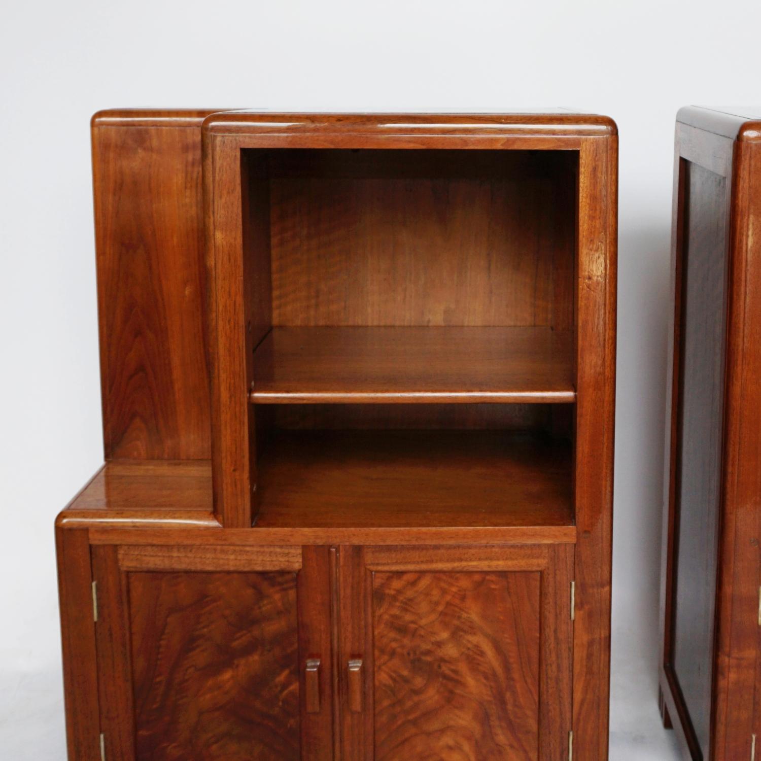 A Pair of Art Deco bedside cabinets by Betty Joel. Two spacious shelves with a two door cupboard below and a stepped alcove to the inside. Figured walnut throughout. Labelled to the back of each bedside. 

Dimensions: H 76cm W 53cm D 30cm