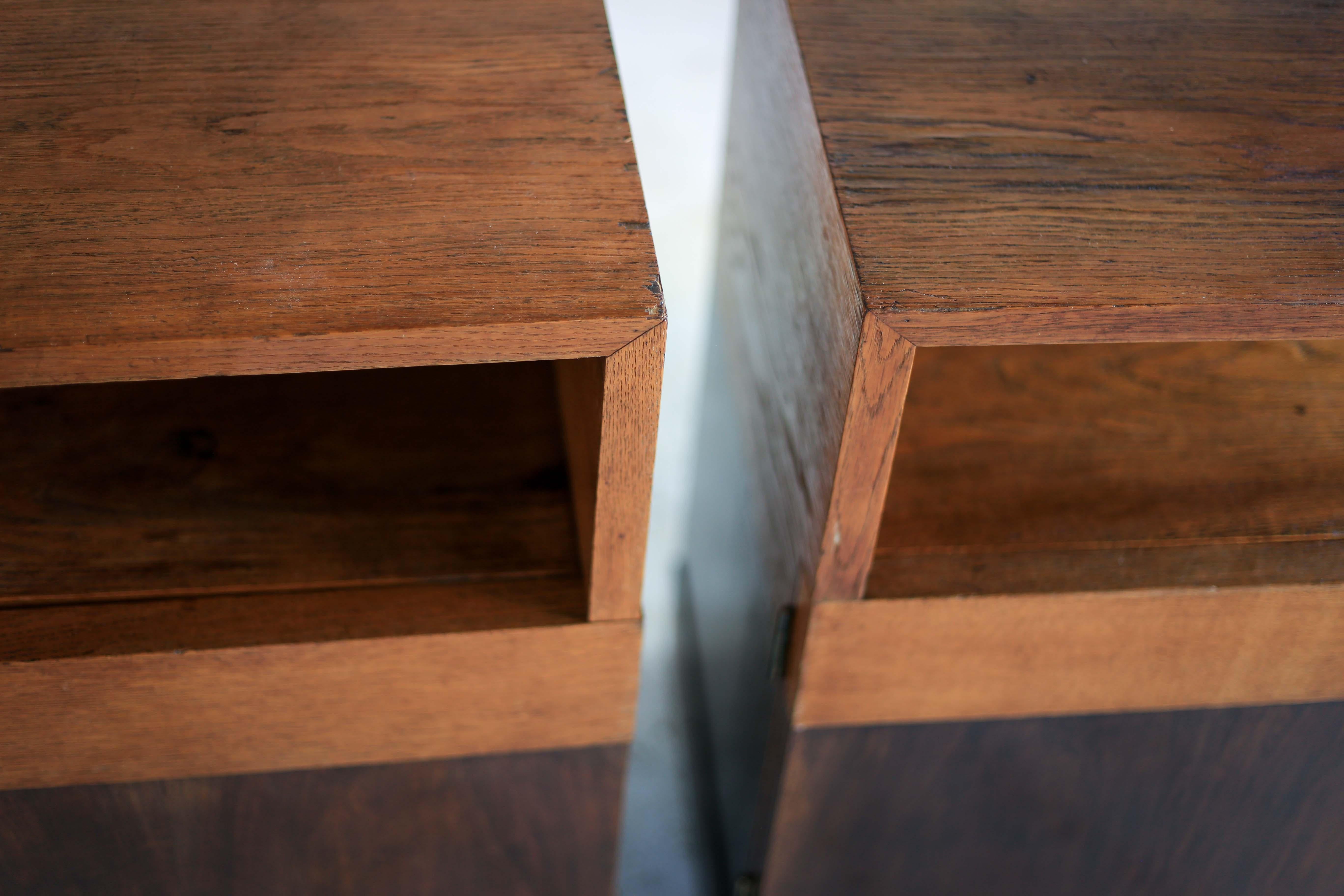 Two Minimalist Art Deco bedside pedestals with a shelved cabinet from the 1940s. They are mostly made from a light oak but with mahogany doors. The condition is still good with a lovely patina, but the veneer on top is a bit worn in places.