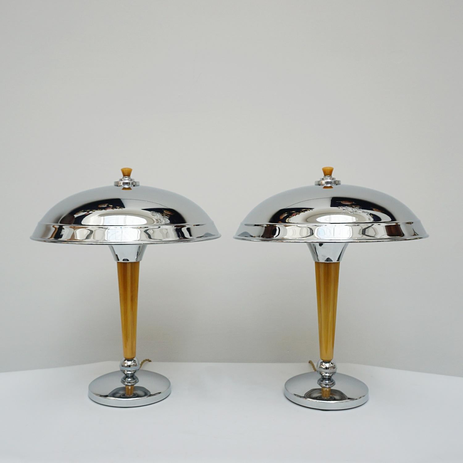 A Pair of Art Deco style dome lamps. Fluted tube of marbled yellow bakelite stem, set over a chromed metal base. Yellow finial topped chromed metal shade. 

Dimensions: H 44cm Diameter of shade: 35cm, of base: 16cm

All of our lighting is fully