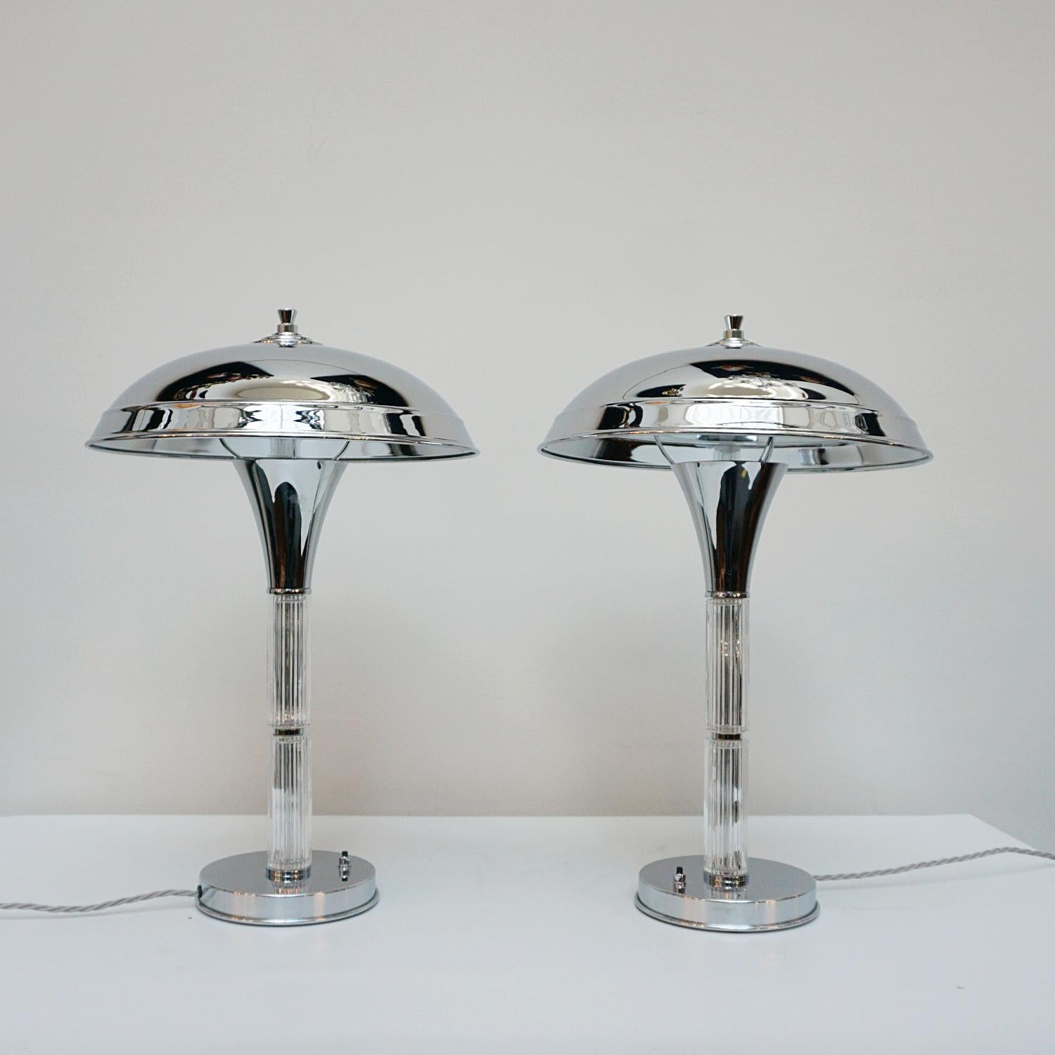 A pair of Art Deco style dome lamps. Glass rod stem double height stem, set over a chromed metal circular base and a chromed metal shade. Chrome finial to top. 

Dimensions: H 55m W 16cm

Origin: English

Item Number: J303

All of our lighting is
