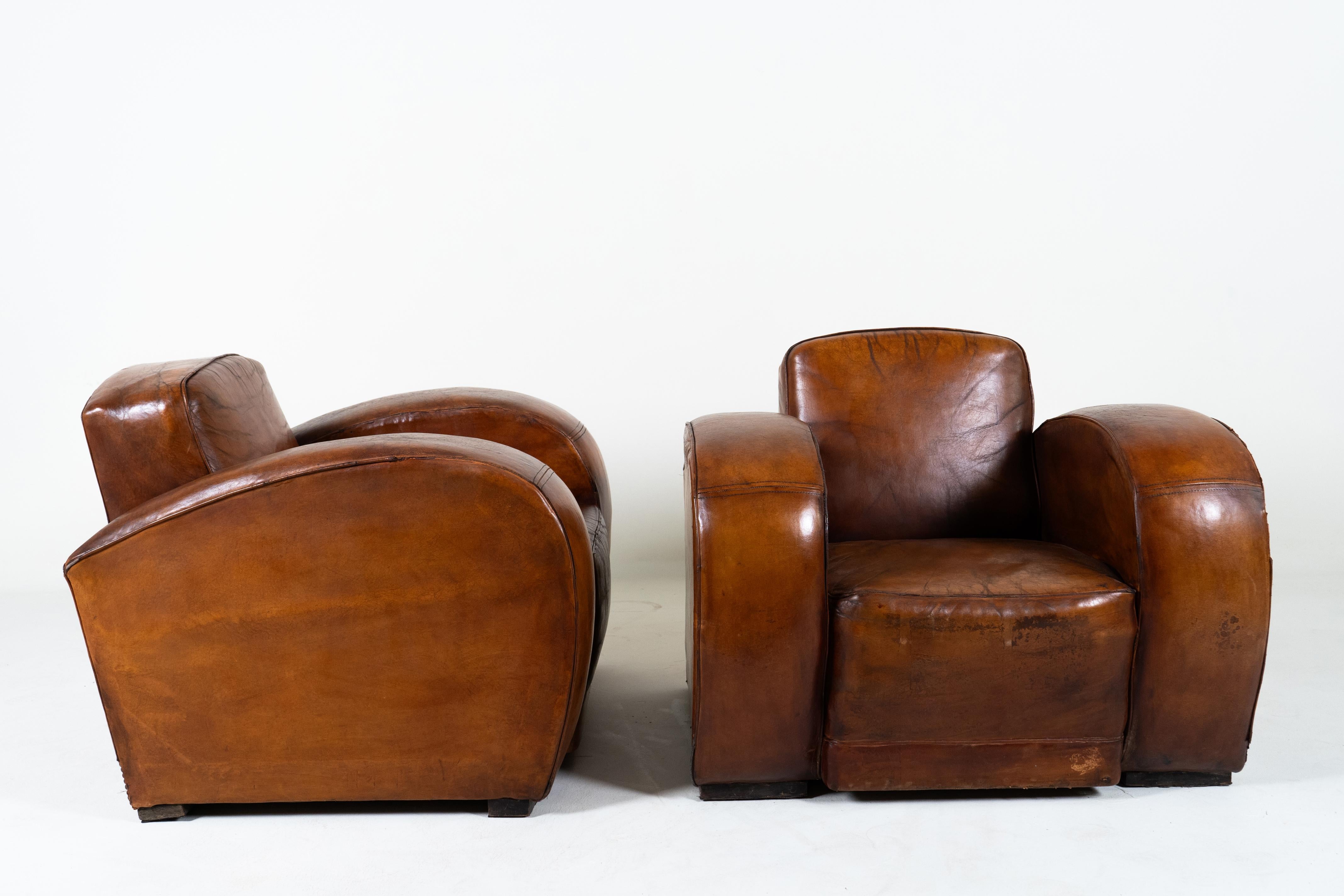 This extraordinary pair of French Art Deco Club chairs dates to the 1930's and epitomizes modern, streamlined design of the period.   They are exceptionally large and voluminous, with sweeping sculptural curves and expanses of soft leather. 