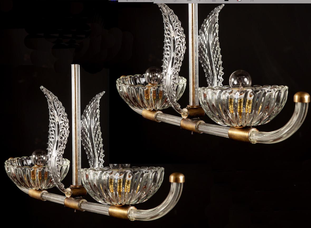 A Beautiful Pair of Italian Art Deco chandeliers by Ercole Barovier , made of clear Murano glass and brass.
 Each with two E 27 light bulbs. 
We can rewire for your country standards. 
They are in excellent vintage condition, the brass with warm