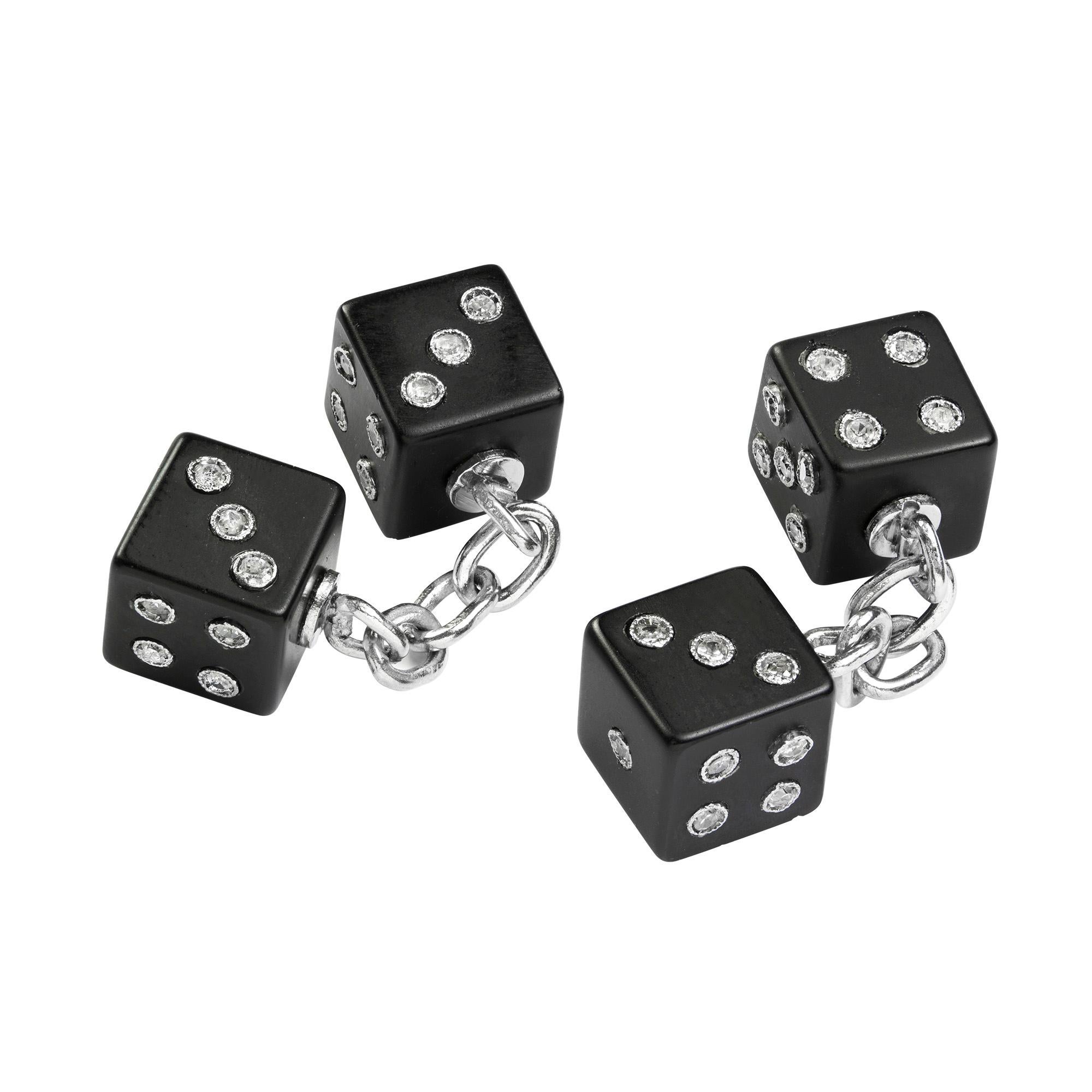 A pair of Art Deco onyx and diamond dice cufflinks, each comprising two square onyx dice, each onyx face measuring 8 x 8 mm, the dots rubover set single-cut diamonds, linked by a white gold chain, circa 1930, each dice measuring approximately