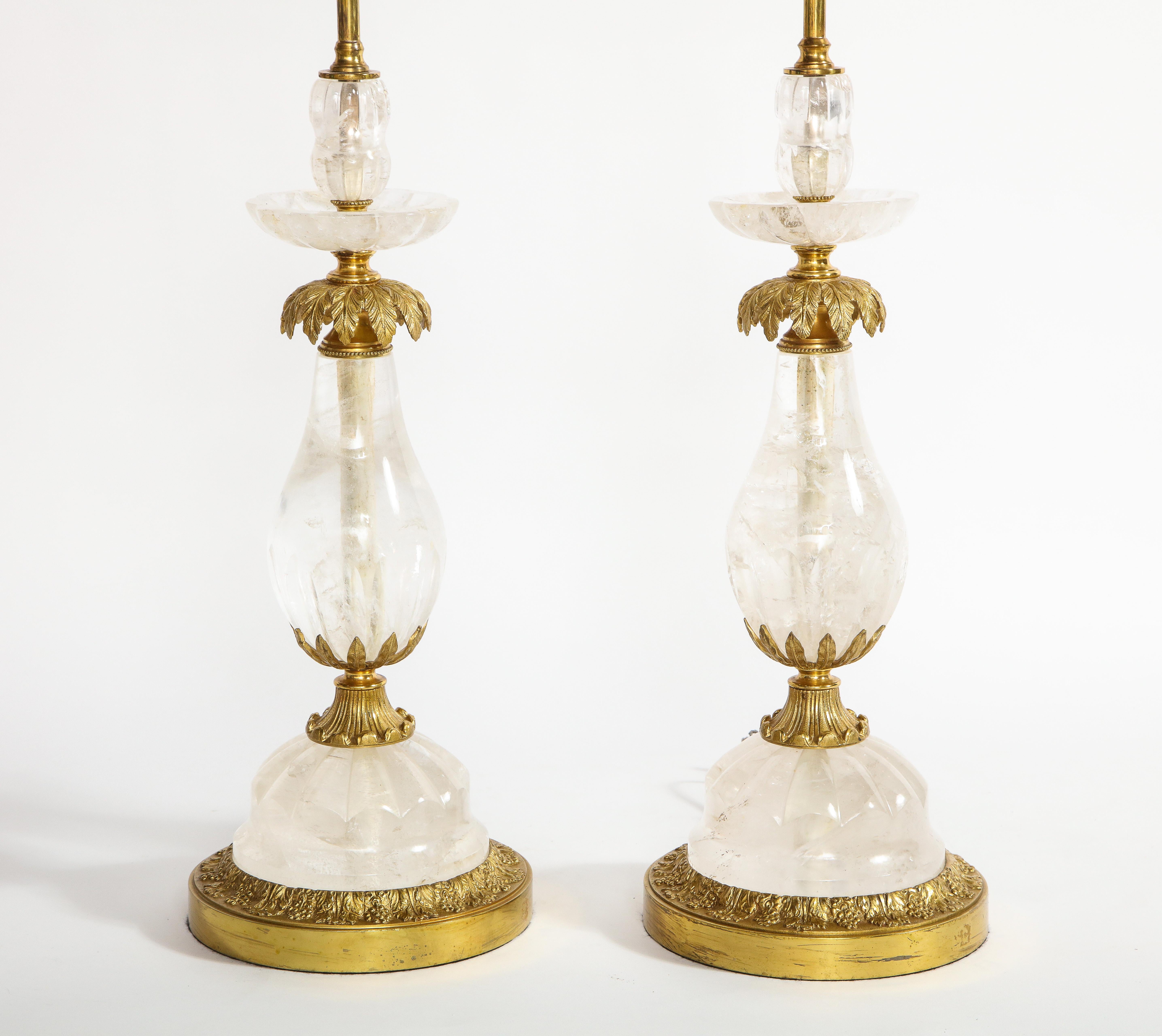 A superb pair of Art Deco ormolu mounted palm tree form clear rock crystal quartz lamps, Attributed to E.F. Caldwell. Each lamp is made with multiple sections of hand carved, polished and faceted clear rock crystal quartz which is surmounted on dore