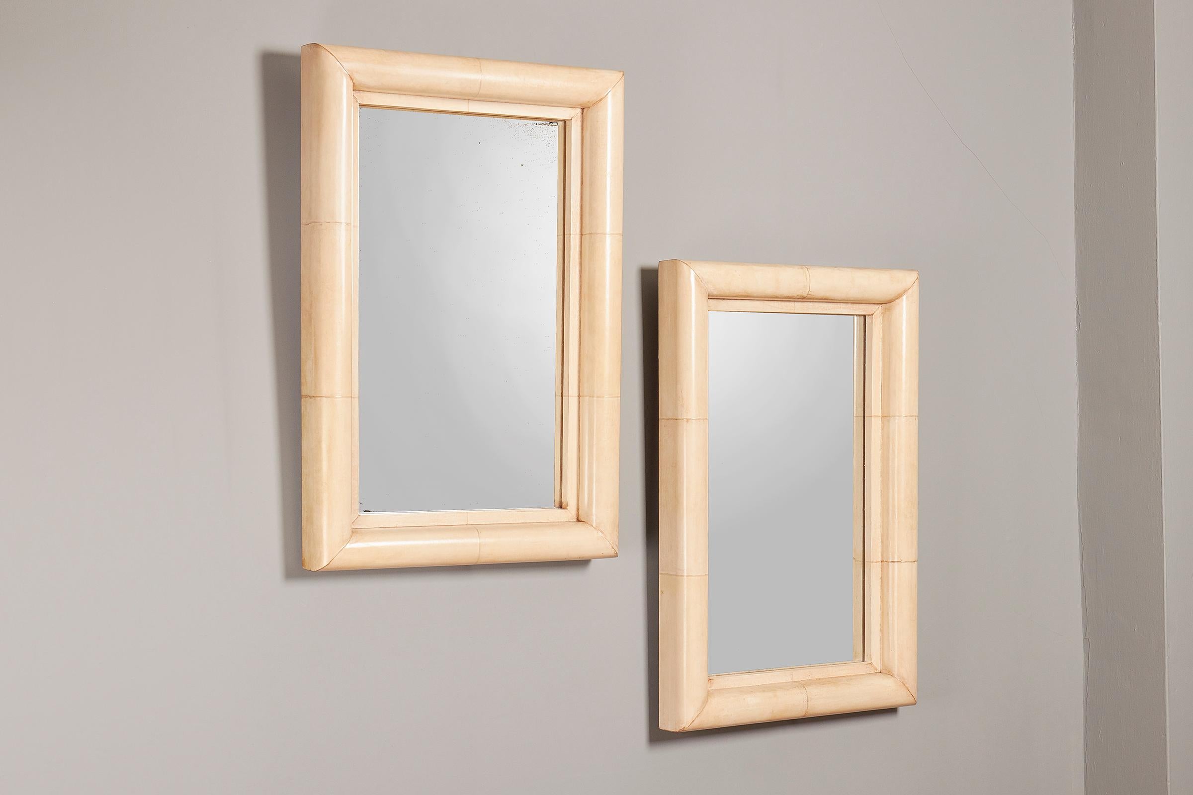 A pair of French Art Deco style parchment covered wood mirrors, circa 1940, ivory colored, rectangular, with cushion frames.