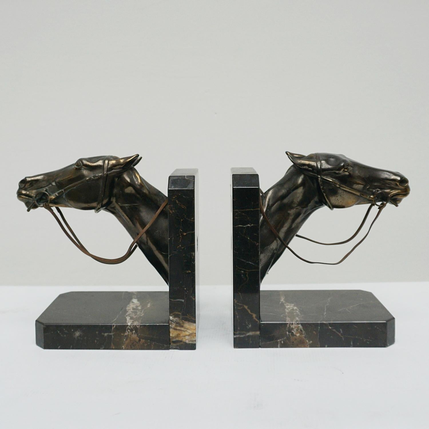 A pair of Art Deco bookends. Two racehorse heads set over marble bases. Original reins. Spelter and marble.