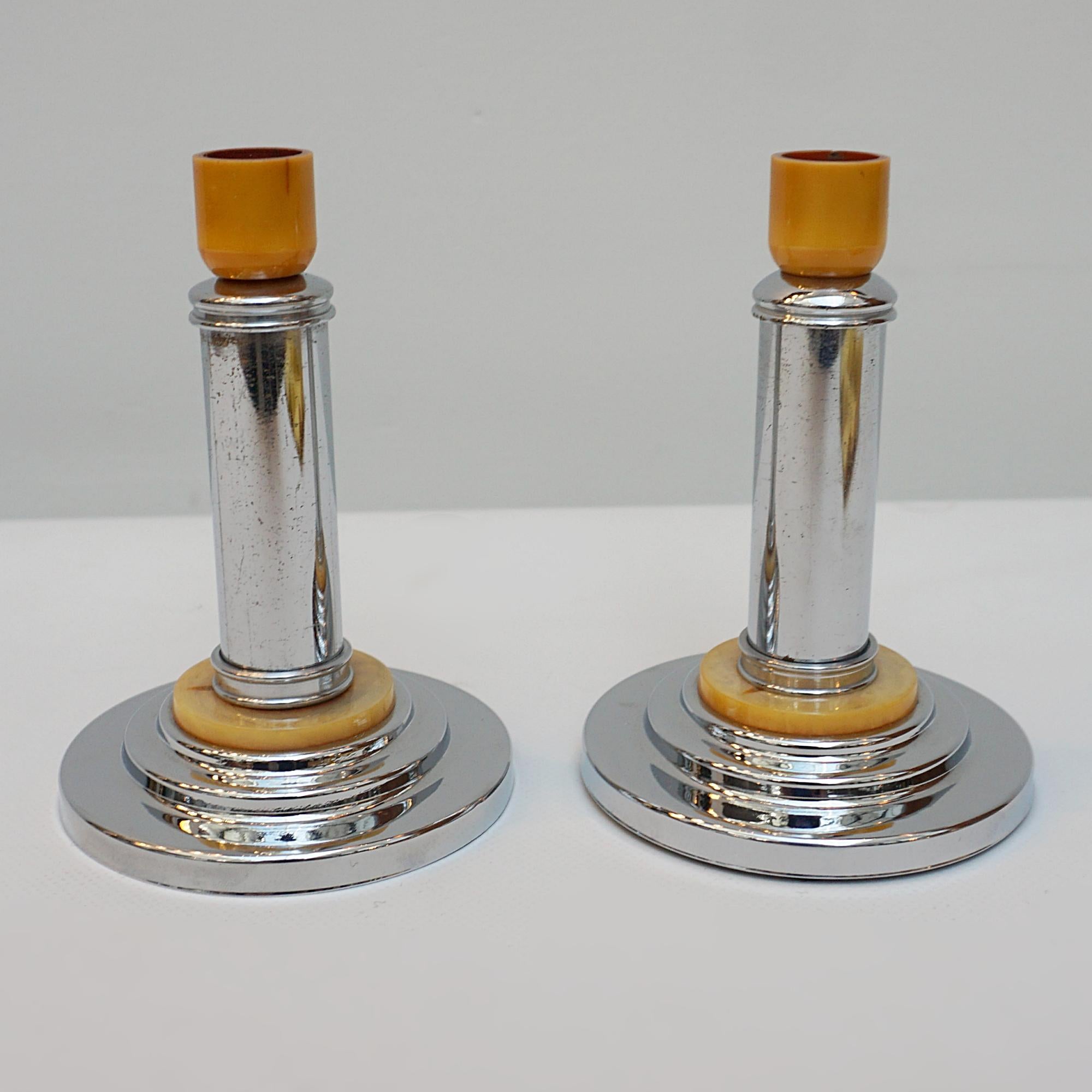 A pair of Art Deco style candlesticks. A chromed cylindrical stem. Set over a rounded, stepped chromed metal base with an amber bakelite ring with amber bakelite candle cup top,

Dimensions: H 13.5cm W 10cm

Origin: English

Item Number: