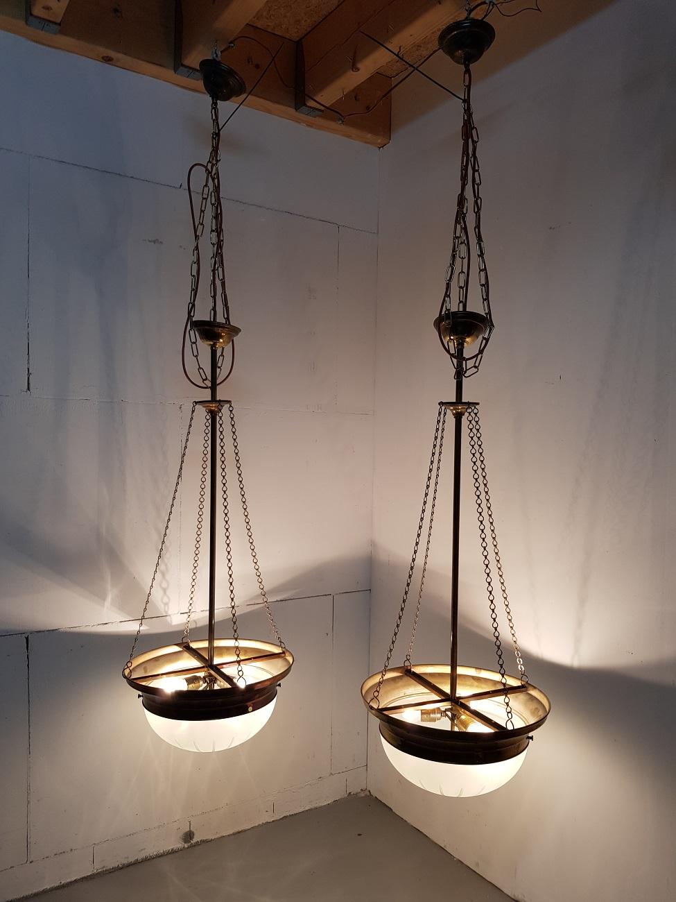 Set of two identical Art Deco style Pendants with 3-light bulbs both are made of a brass frame with glass cover, they are from the Second half of the 20th century (electricity can be renewed for a black vintage fabric wrapped wire). 

They height