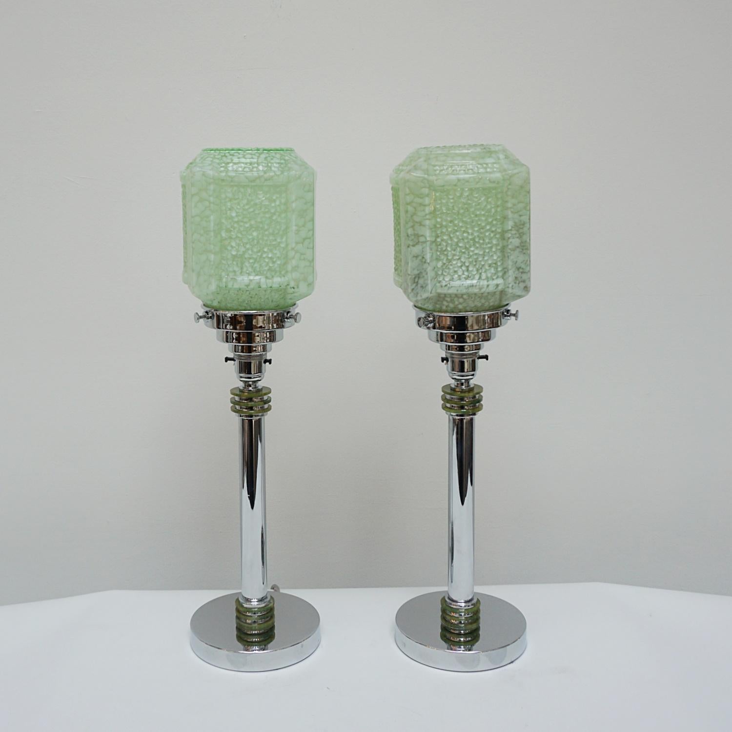 A pair of Art Deco table lamps. Chromed metal stem with discs of mottled green bakelite. Mottled green glass cubic shade, set over a chromed base.

Origin: English

All of our lighting is fully refurbished, re-wired, and re-chromed with some
