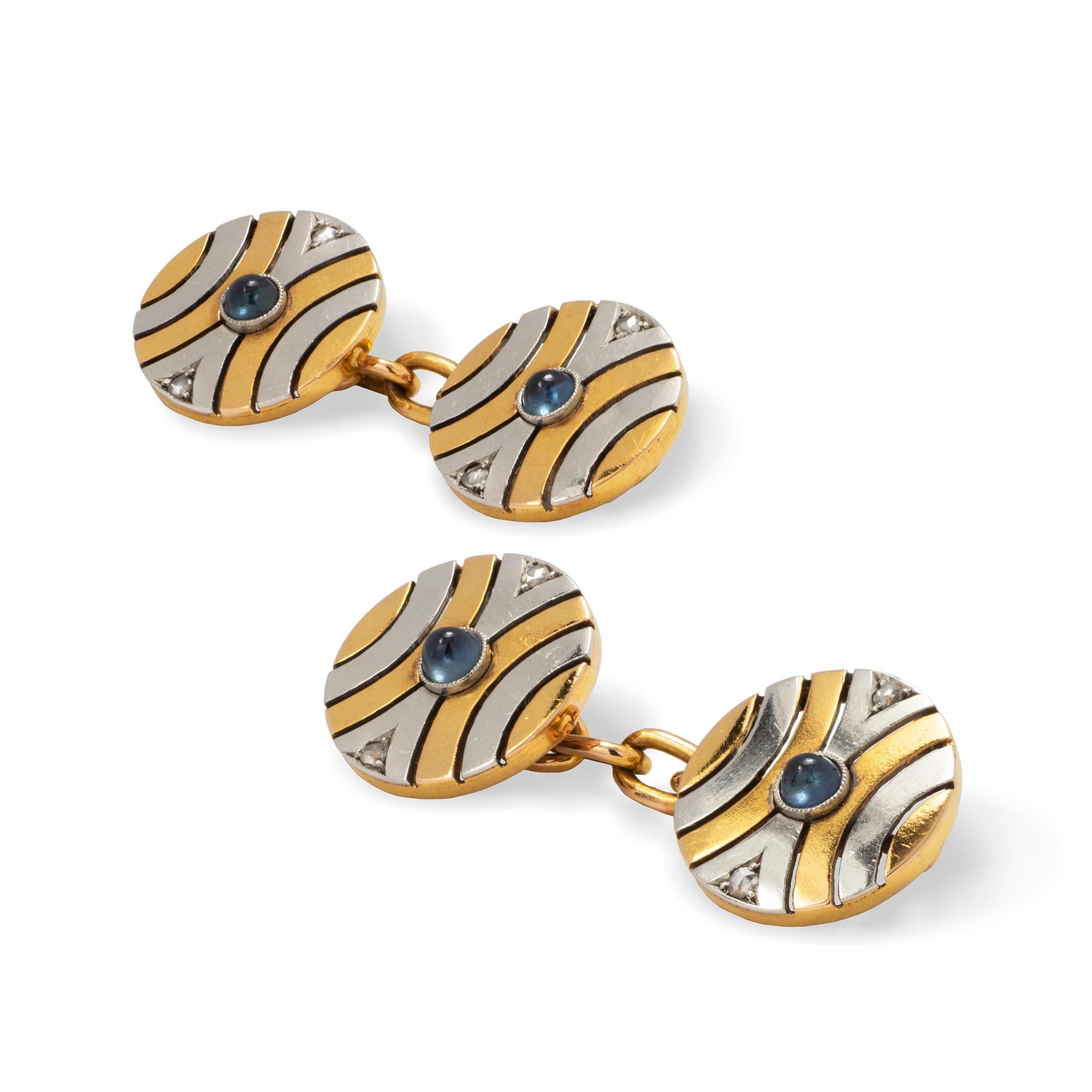 A pair of Art Deco two-colour gold circular cufflinks, each centred with a cabochon sapphire and with two rose cut diamonds, formed as open-work waisted curved sections, circa 1930, measuring approximately 1.3 cm  in diameter, gross weight 7.7