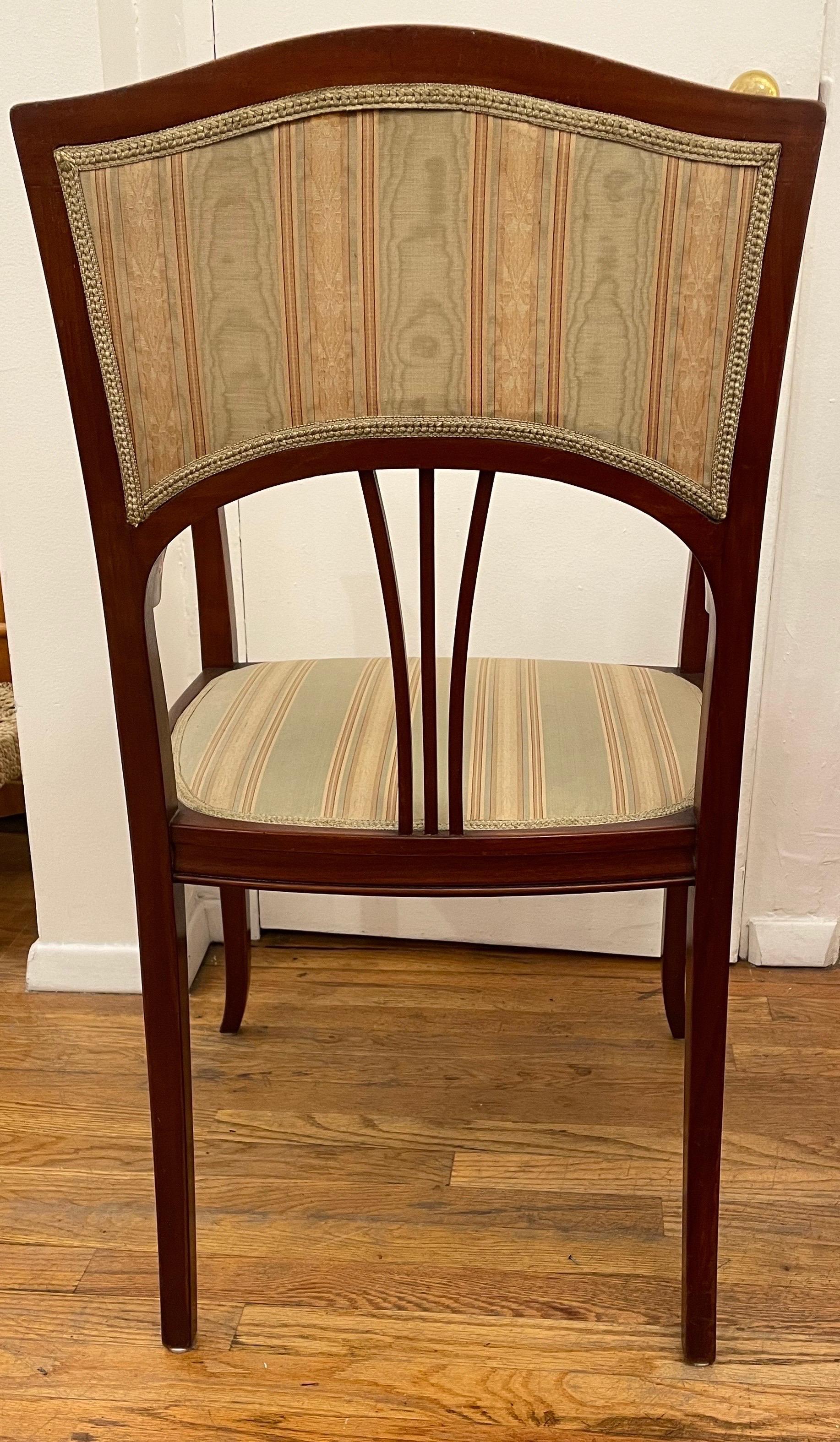 Curves undulate on all surfaces on this pair of beautiful Art Nouveau period armchairs.  Spare and elegant, these strong and comfortable chairs are crafted of solid mahogany and feature the original upholstery which is in serviceable condition.