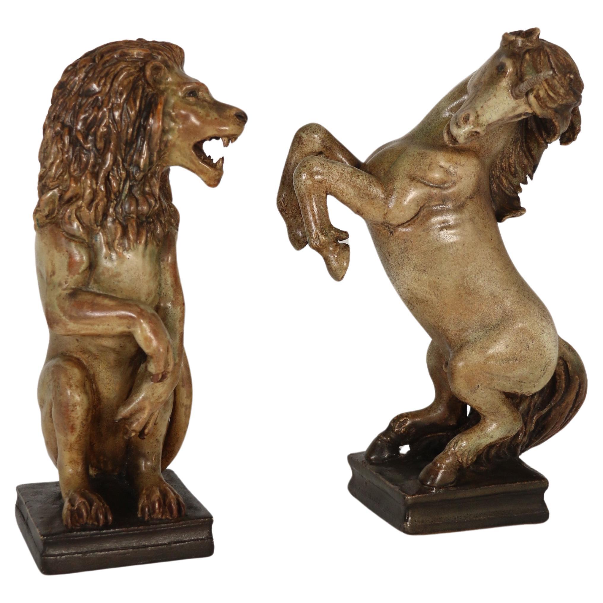 A pair of art pottery hand sculpted figures of a heraldic lion and unicorn.