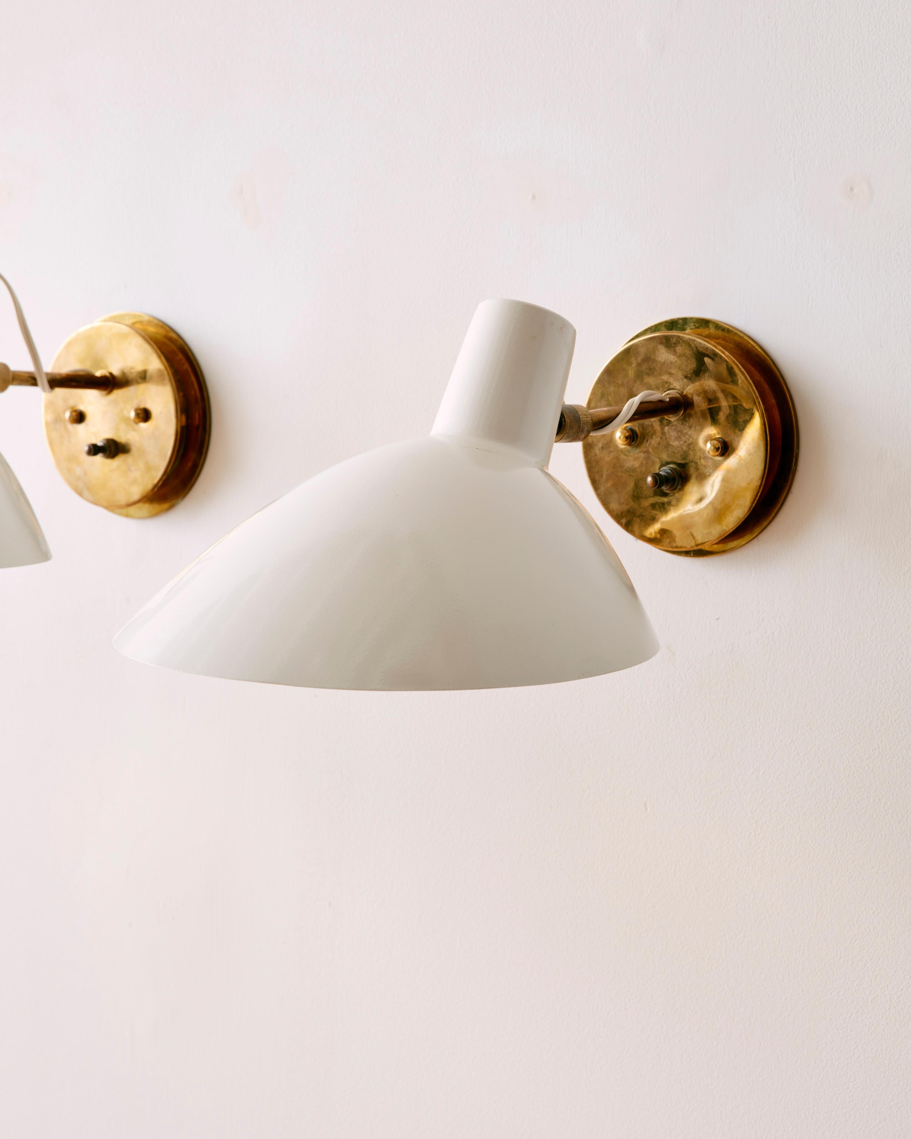 A Pair of Articulated Wall Sconces by Vittoriano Vigano for Arteluce with enameled metal shades and brass hardware. 

Vittoriano Viganò (1919–1995) was an Italian architect and lighting designer known for his innovative contributions to mid-century