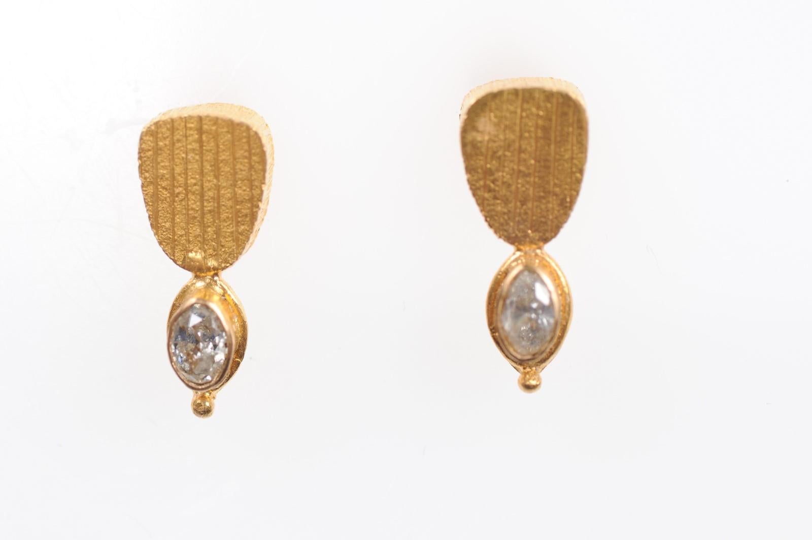 A pair of artisan designed one of a kind dangling earrings created out of 22-karat gold and diamonds. This elegant pair of earrings feature a nicely textured 22 kg gold upper plaque in vertical lines, with oval shaped bezels set below with