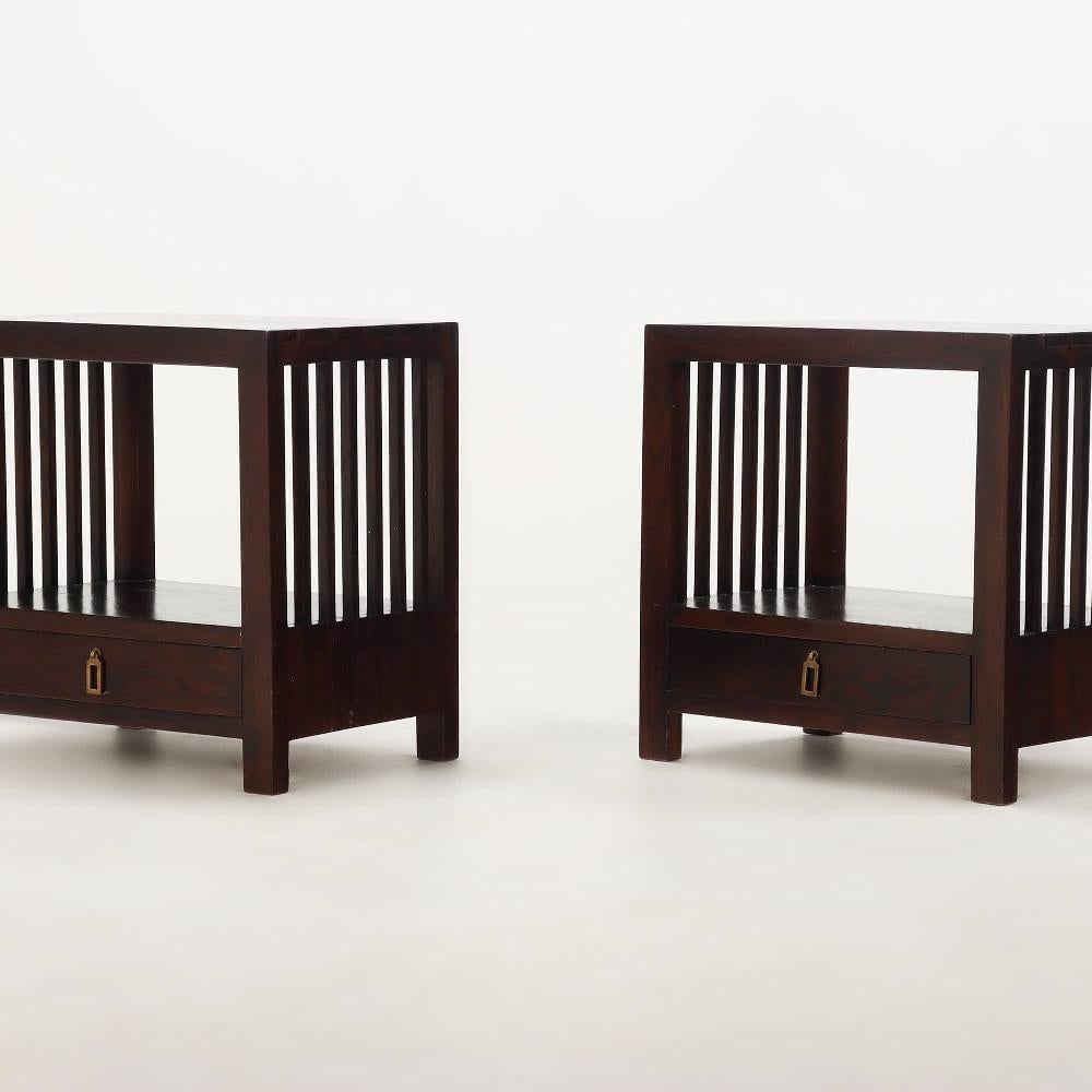 Una coppia di comodini ben realizzati in stile Arts and Crafts, ciascuno costruito in quercia tinta con lati a doghe verticali. Il design è caratterizzato da due ripiani aperti e da un unico cassetto inferiore con tiretti in ottone massiccio, che