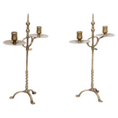 Un par de candelabros de latón Arts and Crafts de doble rama y altura regulable