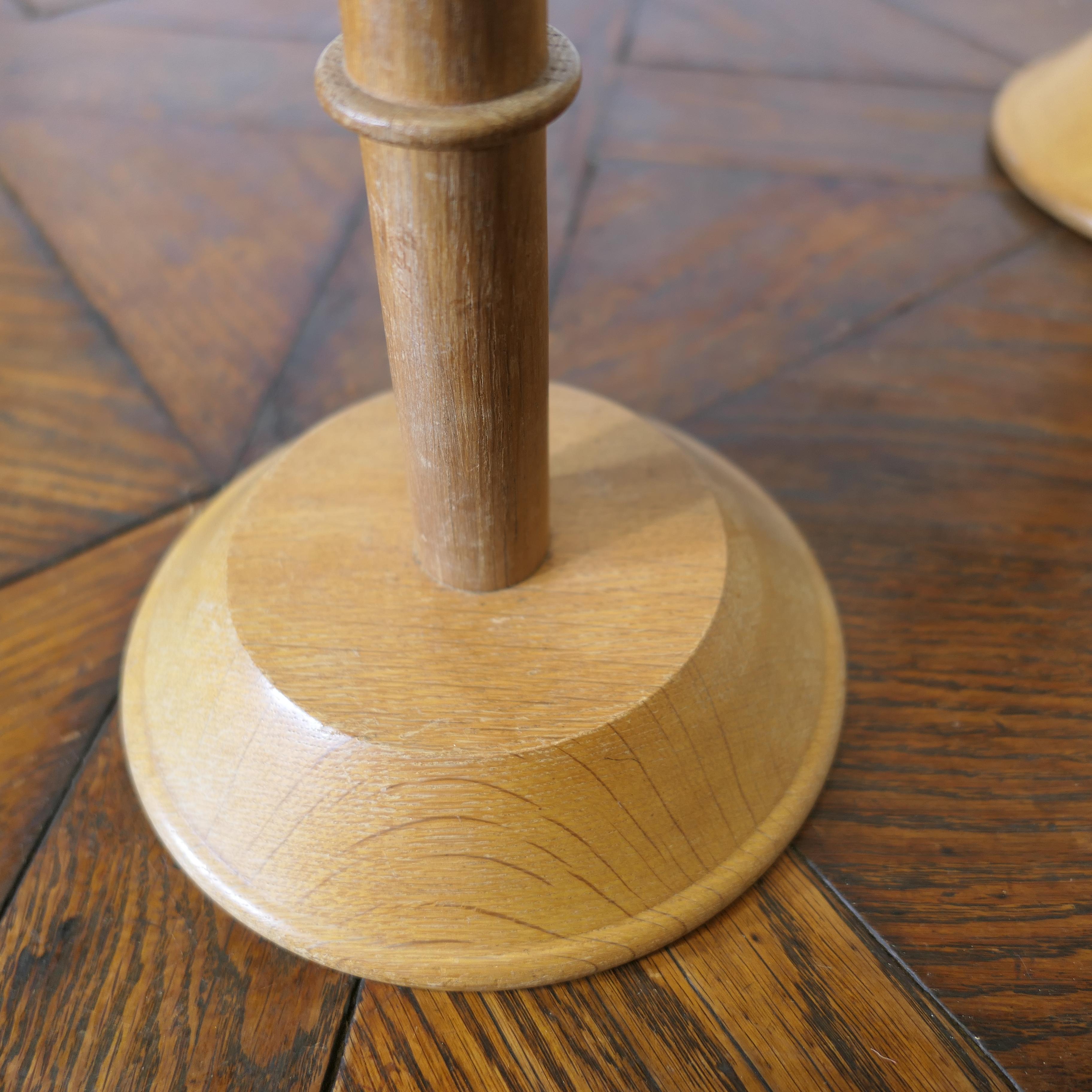 A Pair of Arts and Crafts Golden Oak Hat Stands Shop Display

The stands have a neatly turned upright column set with a round tweed pillow hat support the is soft to allow it to be used with pins if necessary   
These are a charming and stylish pair
