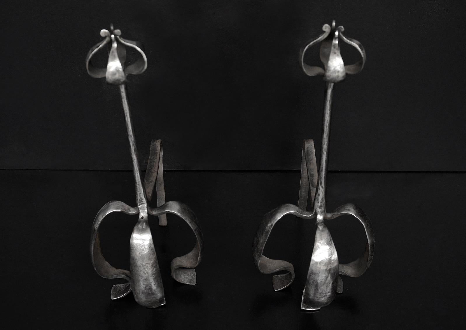 A pair of polished Arts & Crafts wrought iron firedogs with shaped feet and shaped petal finials. English. Early 20th century.

Measures: Height: 535 mm 21