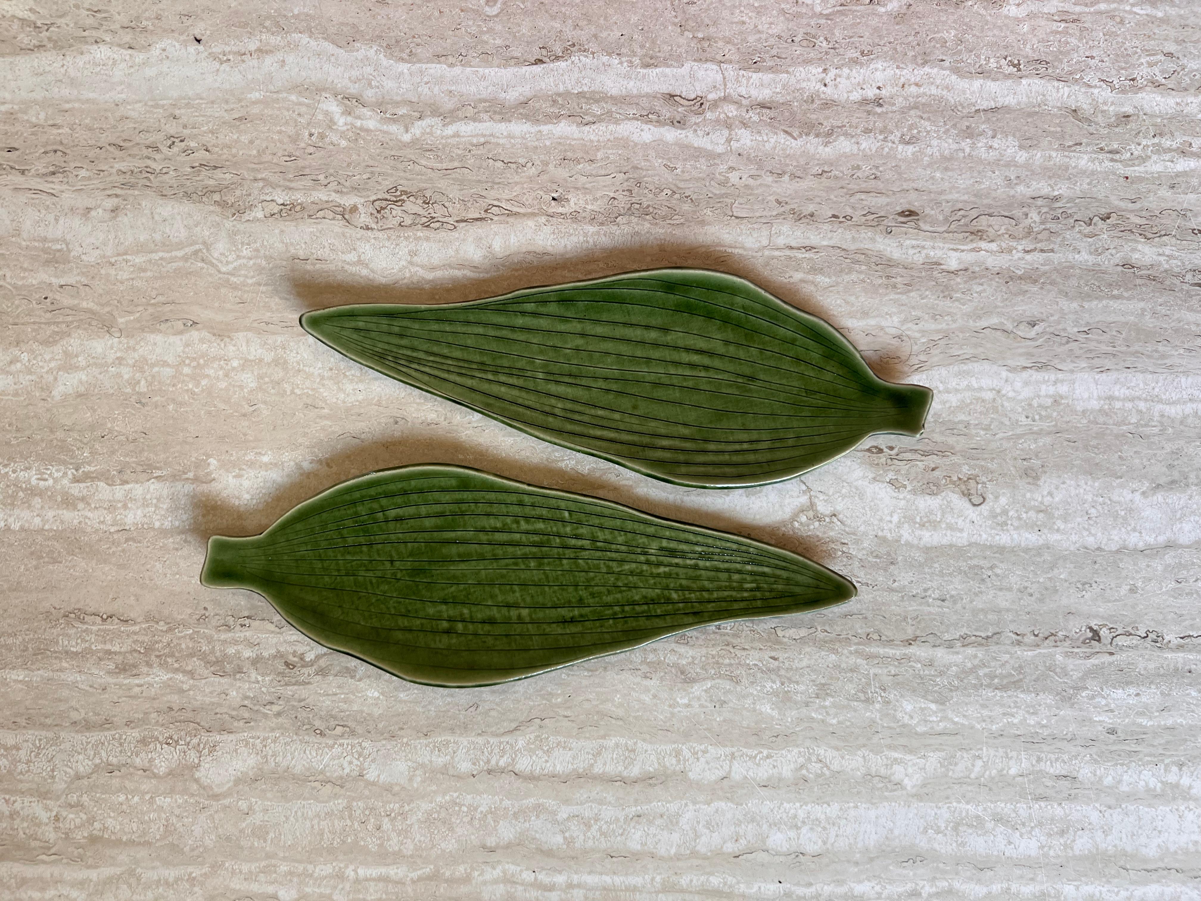 A pair of vintage Asian ceramic and glazed dishes depicting broad leaves, 1970s. From Japan, mid 20th century. A serene grass green hue with the leaf veins etched in. Fabulous condition. 
10.5” W x 3.75” D x .25” H.