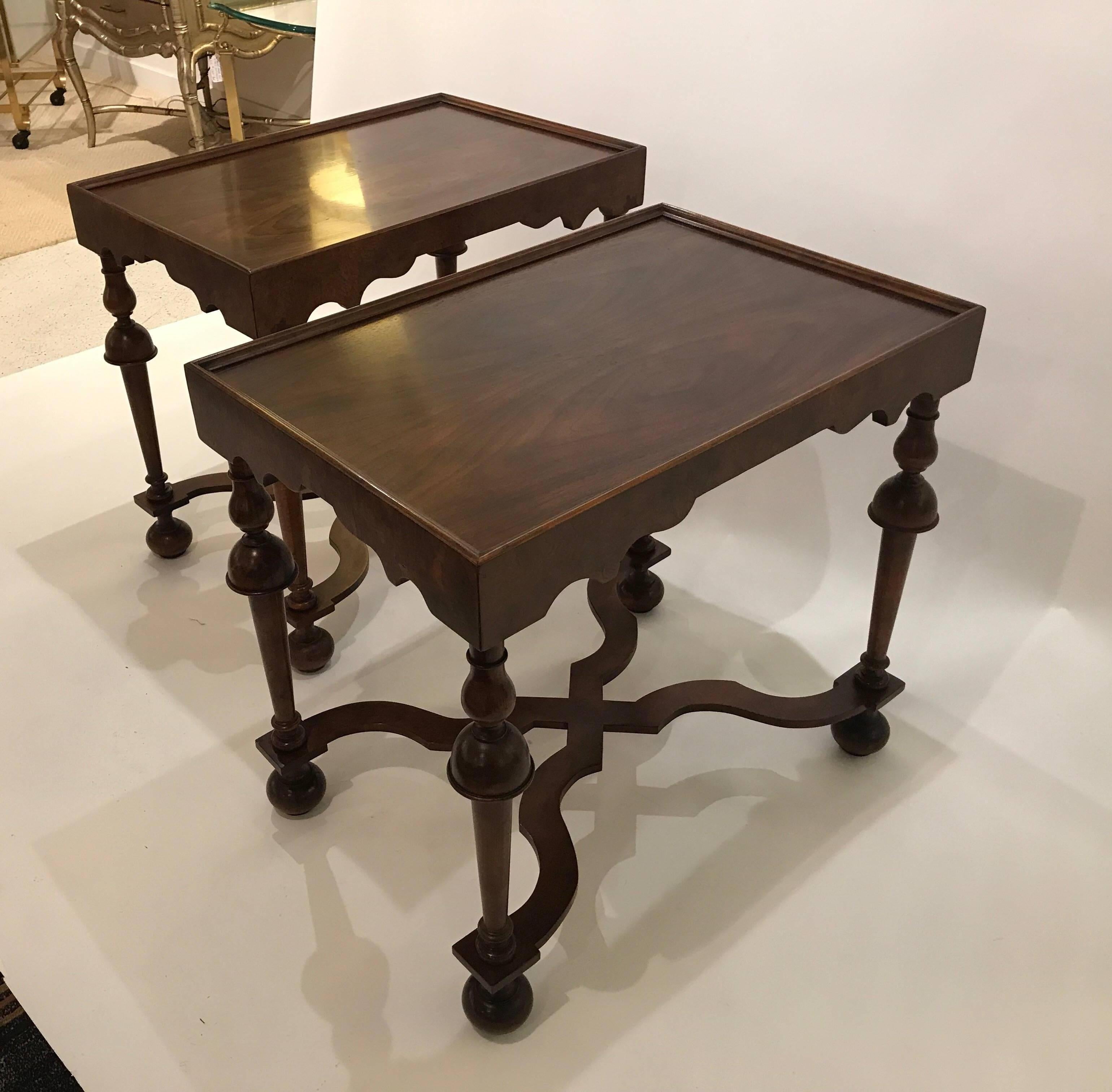 A pair of Baker Furniture end tables in the Tudor style. The figurative grained walnut tops supported buy four turned legs supported by shapely stretchers.