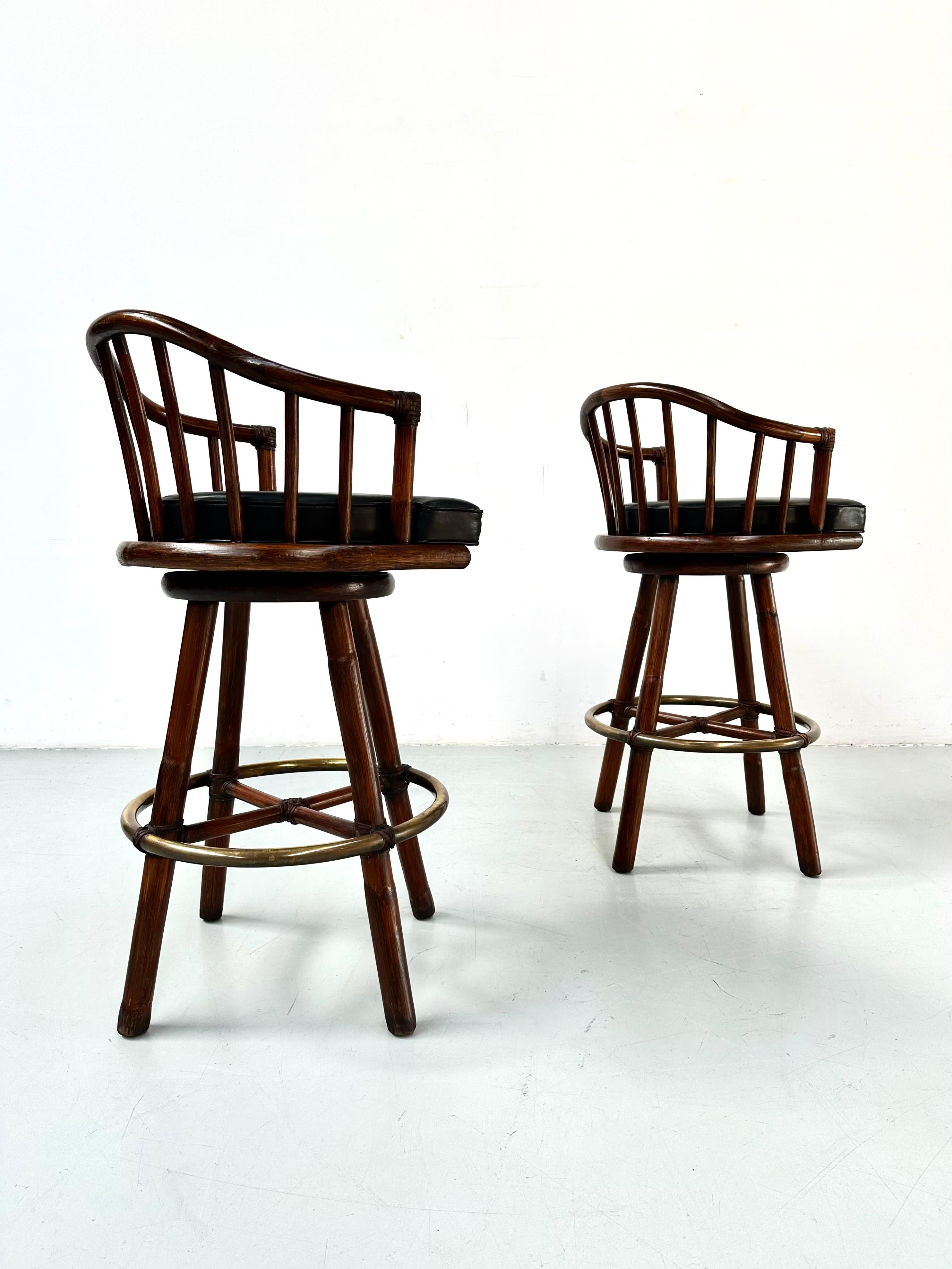 A great pair of bamboo and Brass barstools designed by the Dutchman Hans Kaufeld  for McGuire in the seventies. Featuring swivel leather covered seats. These barstools are made with the famous McGuire rawhide strapping and Classic brass foot rail. 

