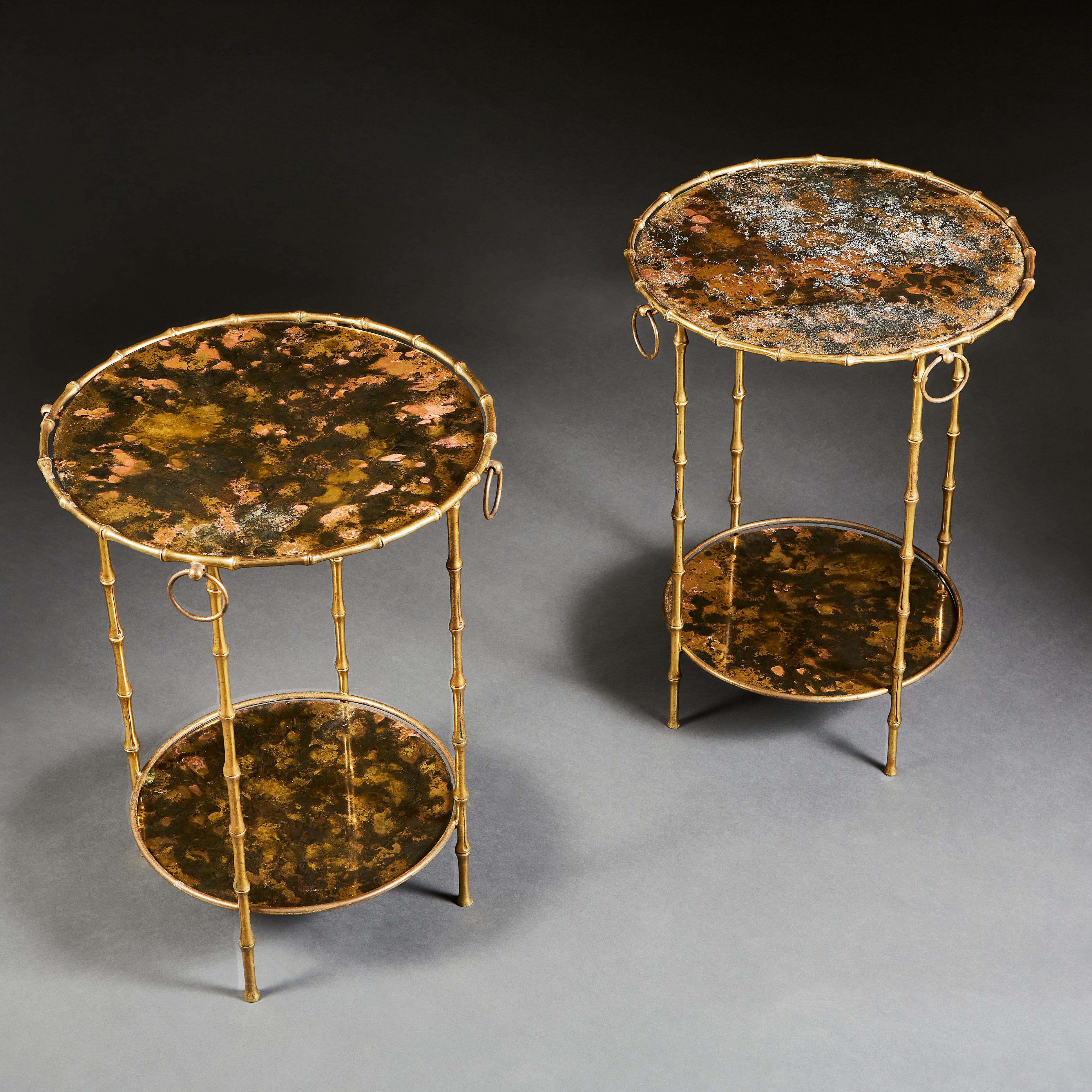 A pair of circular bamboo simulated brass étagères, the tops with patinated metal under glass, with four loop handles punctuating the edges of top tier.
