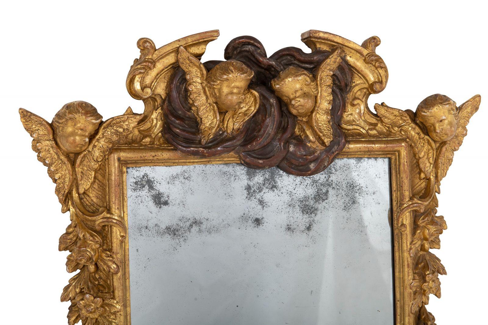 Introducing a Pair of Baroque Giltwood and Gesso Wall Mirrors from Circa 1700 and later. This remarkable set offers a touch of 18th-century grandeur, featuring rectangular plates framed with intricate 'C' scrolls, flowers, and winged cherubs. The
