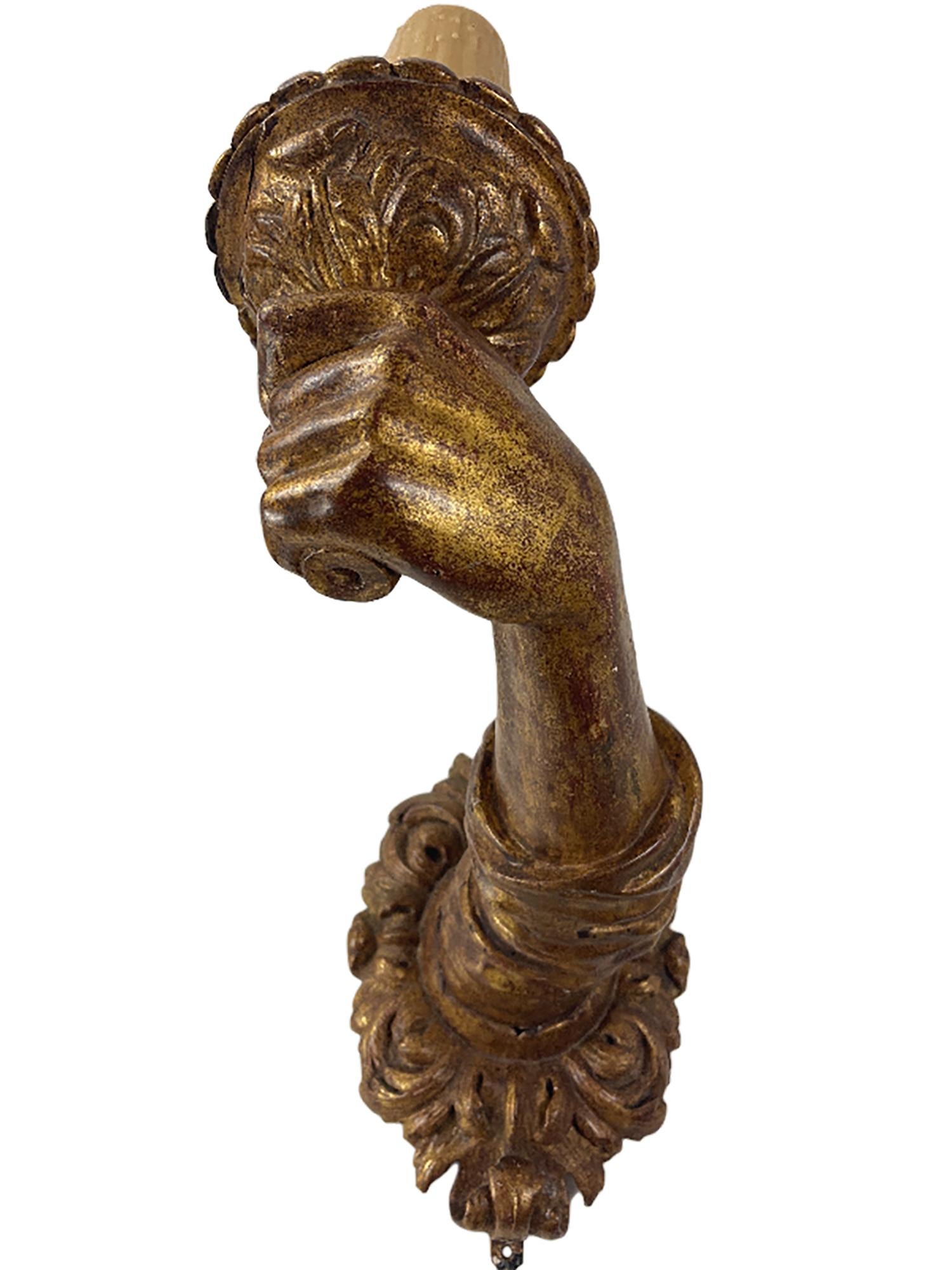 Une belle paire d'appliques en bois doré sculpté à la main, de style baroque italien du 17ème siècle. 

Les bases florales et les manches pliés sont sculptés de manière complexe et les bras assortis sont courbés. Les bras tiennent des torches