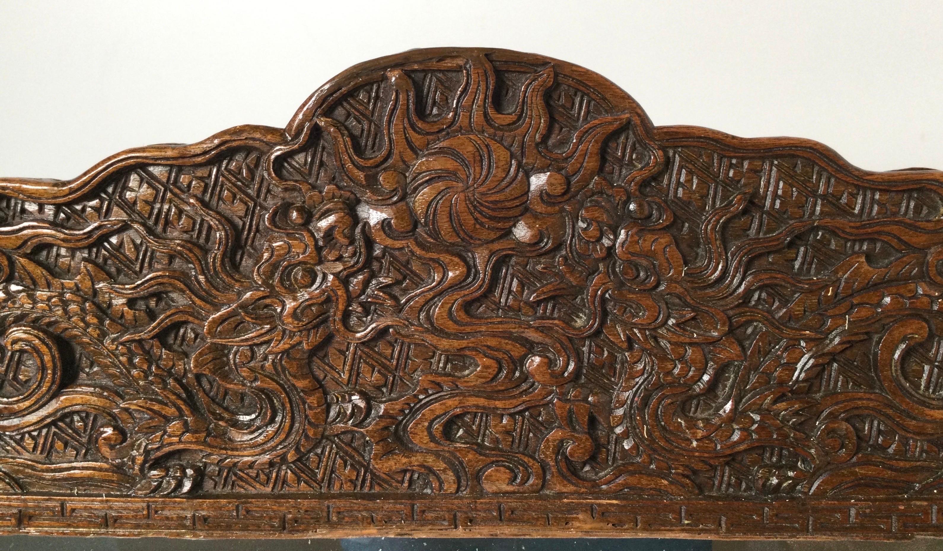 A pair of Asian hand carved framed mirrors with beveled glass. The delicately carved frames with dragons, scrolling and symbols, with carving along the outside edge. Measures: 22 wide, 21 high.