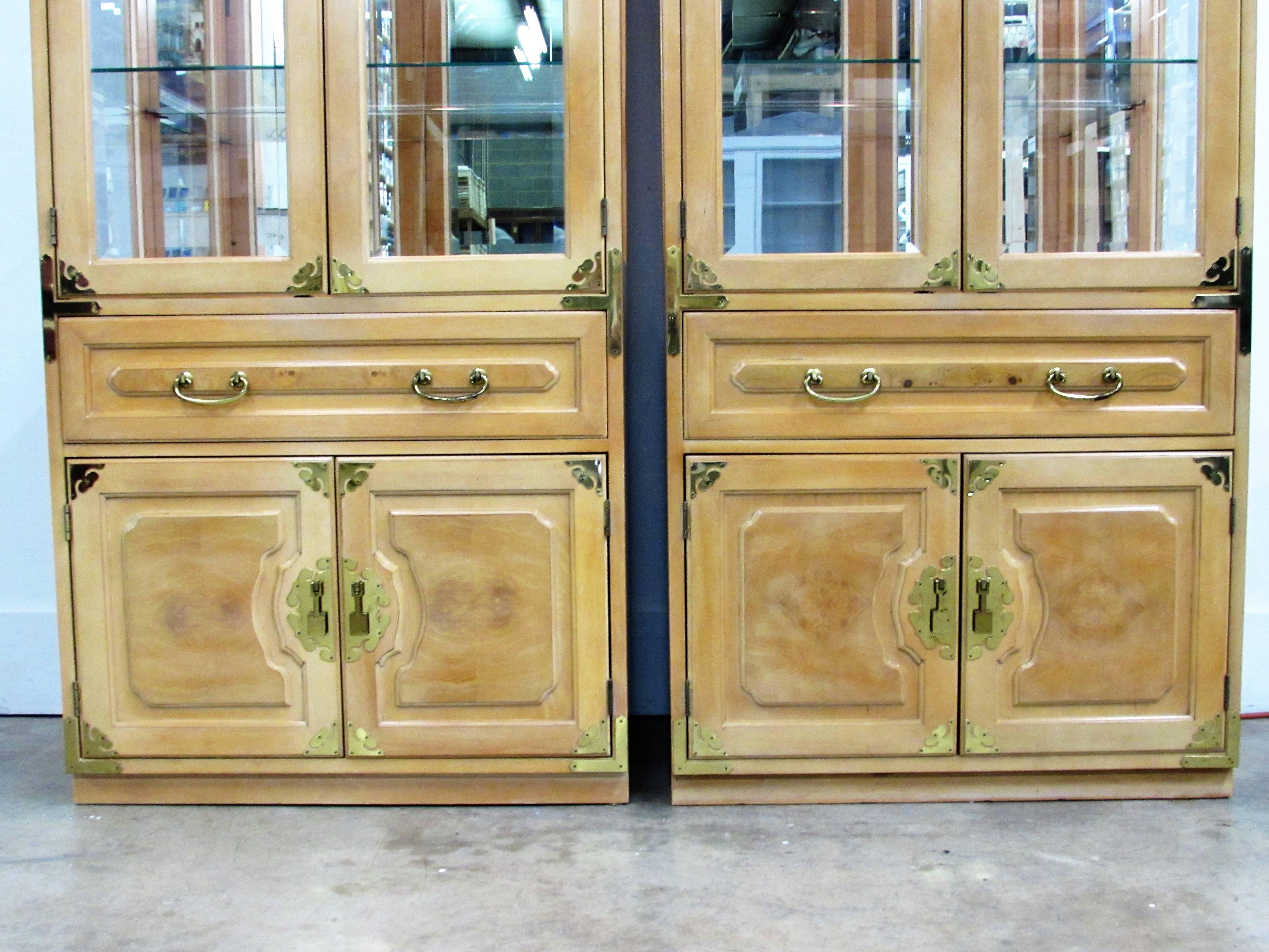 A pair of Bernhardt chinoiserie cabinets in the original blonde finish, two swinging doors open to three adjustable shelves with etched grooves with mirror in back and glass on both sides and working light above, over one elongated dovetail drawer