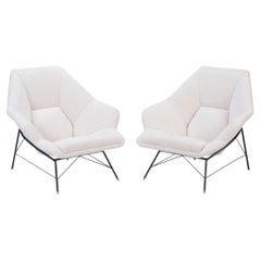 A pair of black iron frame club chairs with white upholstered seats.