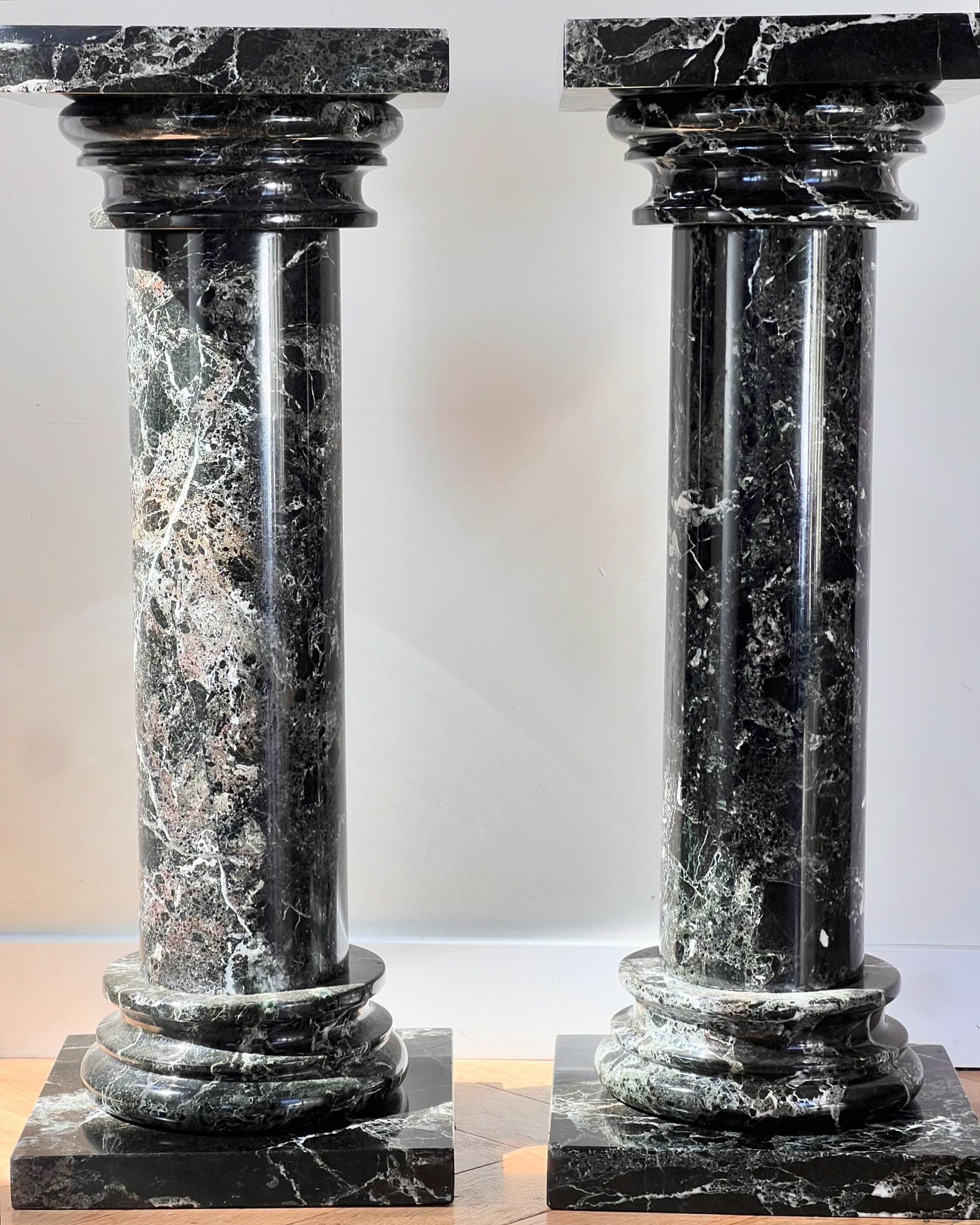 A pair of neoclassical marble pedestal columns, late 20th century. Probably hailing from Italy, this handsome pair of columns is of the deepest licorice black featuring stunning intricate veining in tones of cream and truffle. One column dismantles