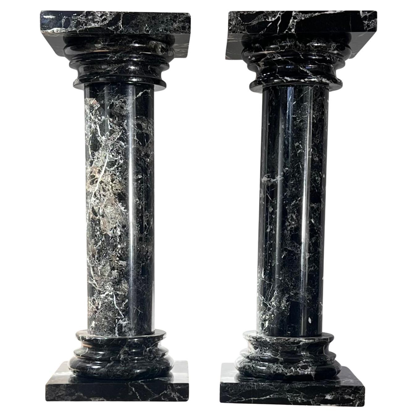 A pair of black marble pedestal columns, late 20th century