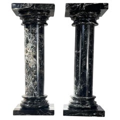 A pair of black marble pedestal columns, late 20th century