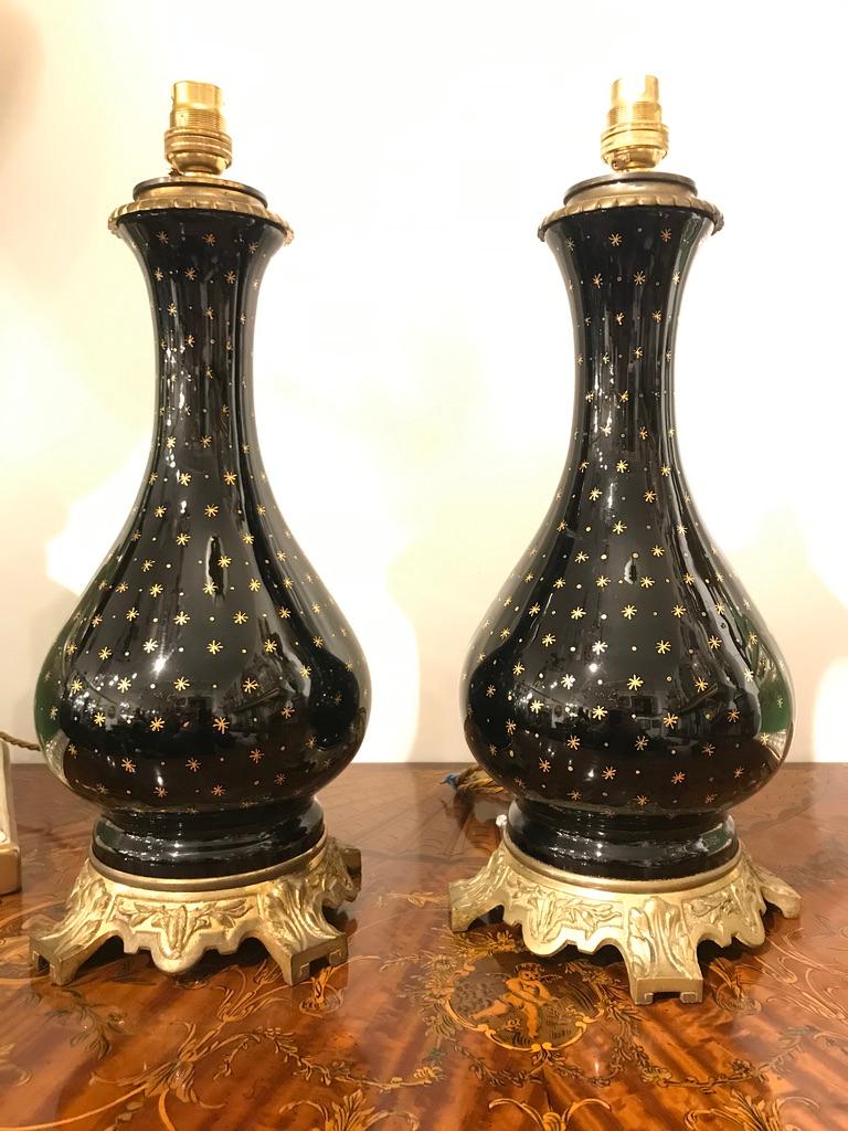A 19th century pair of black Porcelain lamps on ormolu bases with gold star detailing.