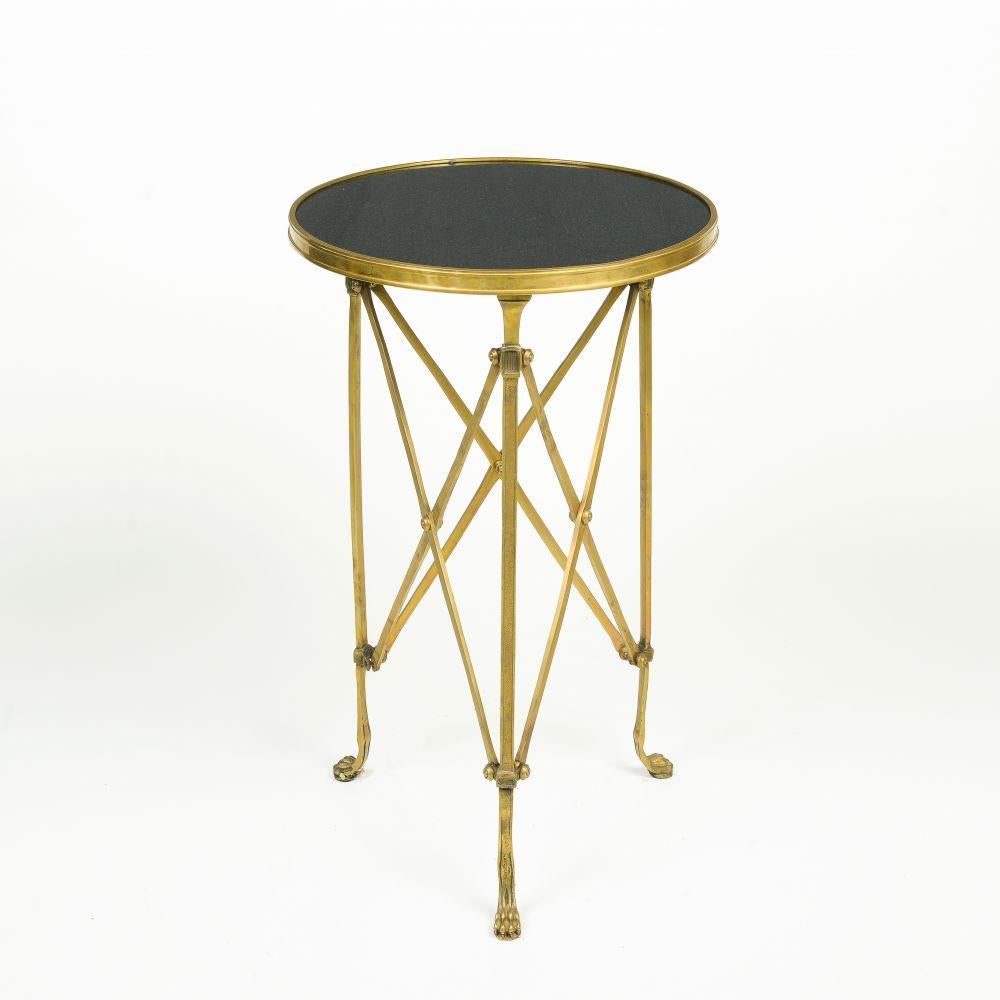 The round stone tops trimmed in brass, supported by an elaborate brass stretcher, with three legs terminating in claw feet.