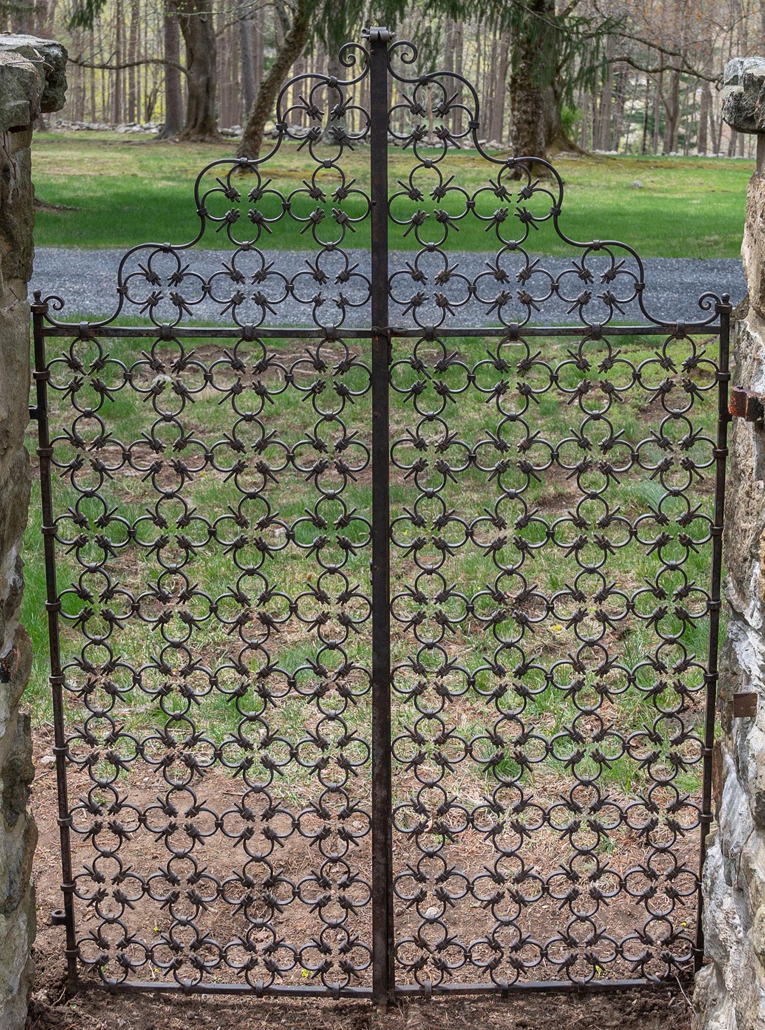 A fine pair of wrought-iron gates in the style of Samuel Yellin, with all-over quatrefoil motif and scalloped top edge, American, ca. 1900. Measures: 68 ins. high overall, 46 ins. wide overall.