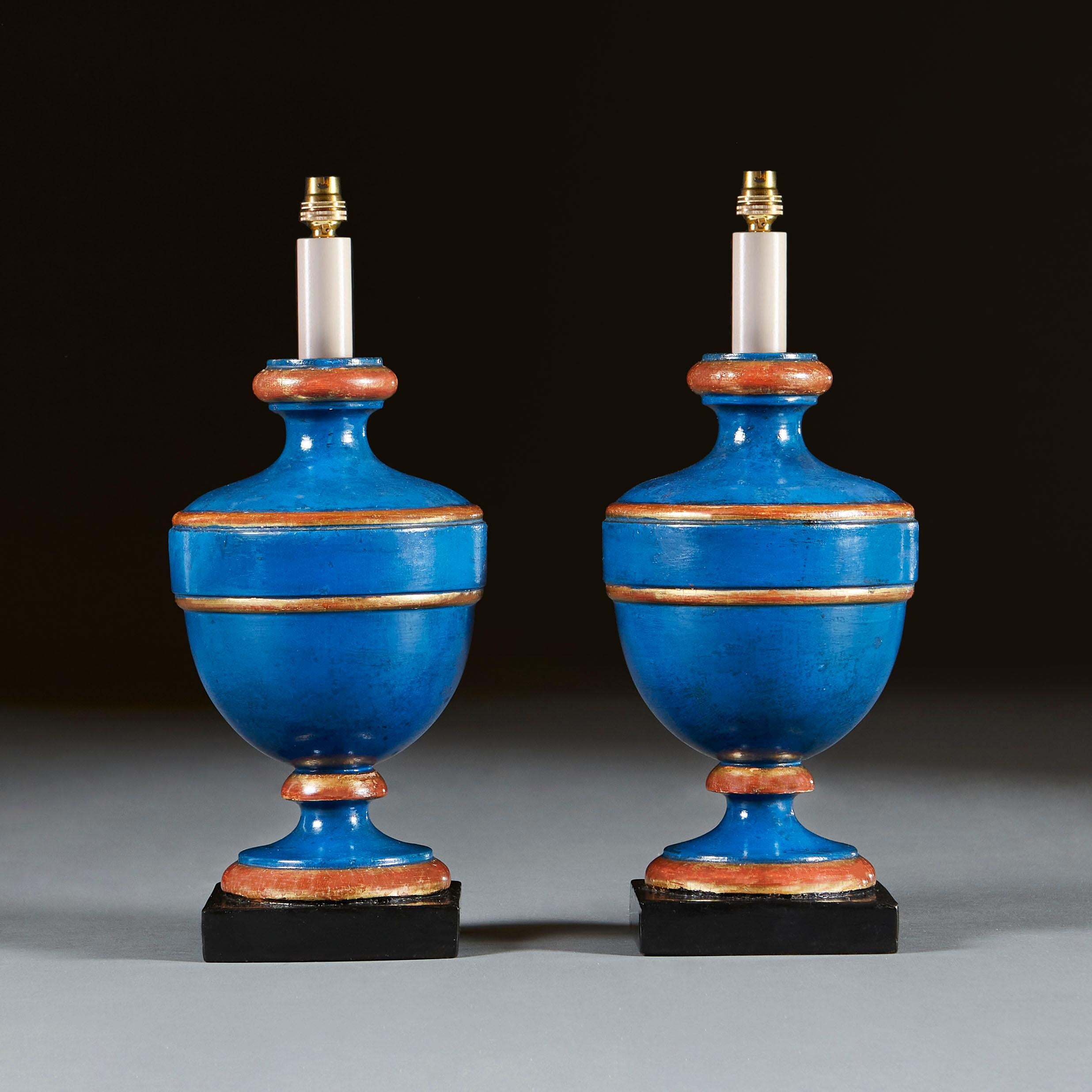 A pair of late nineteenth century baluster candlestick lamps, with blue painted ground throughout, with gilt bands, all supported on ebonised square plinths.