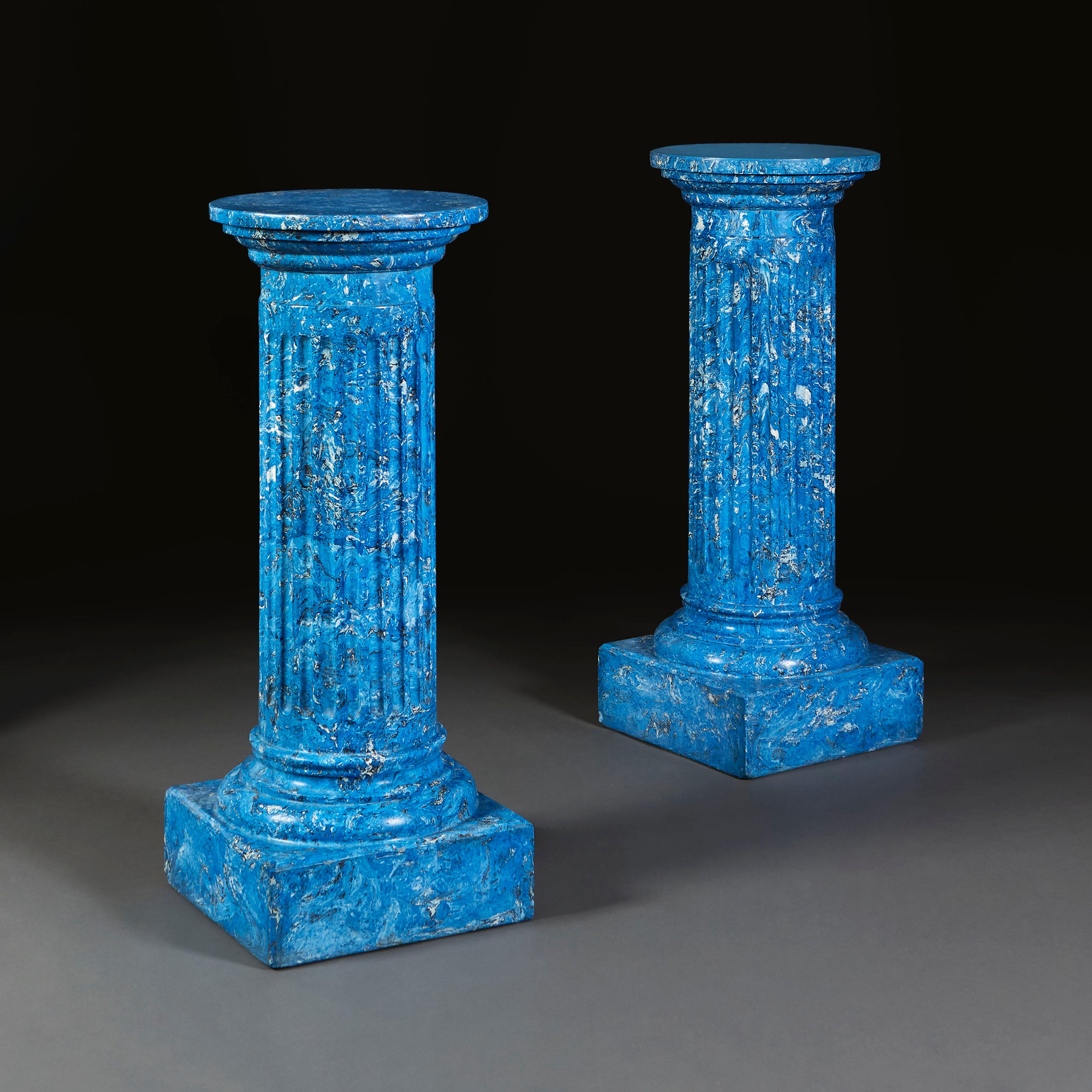 A pair of blue scagliola column plinths, with circular tops, fluted columns, and all supported on square plinth bases.