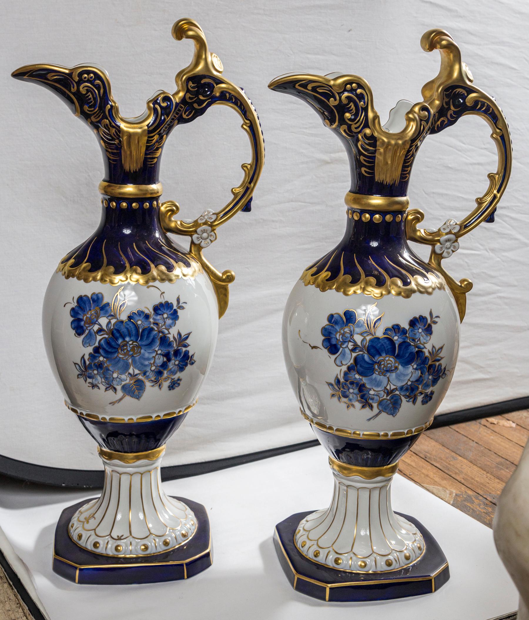 This pair has a blue and gold top section, including the handle, a white mid section with blue flowers , a lower section, concluding base with gold and white above a cut corner blue and gold base.
The handle is 5 inches from the body at its