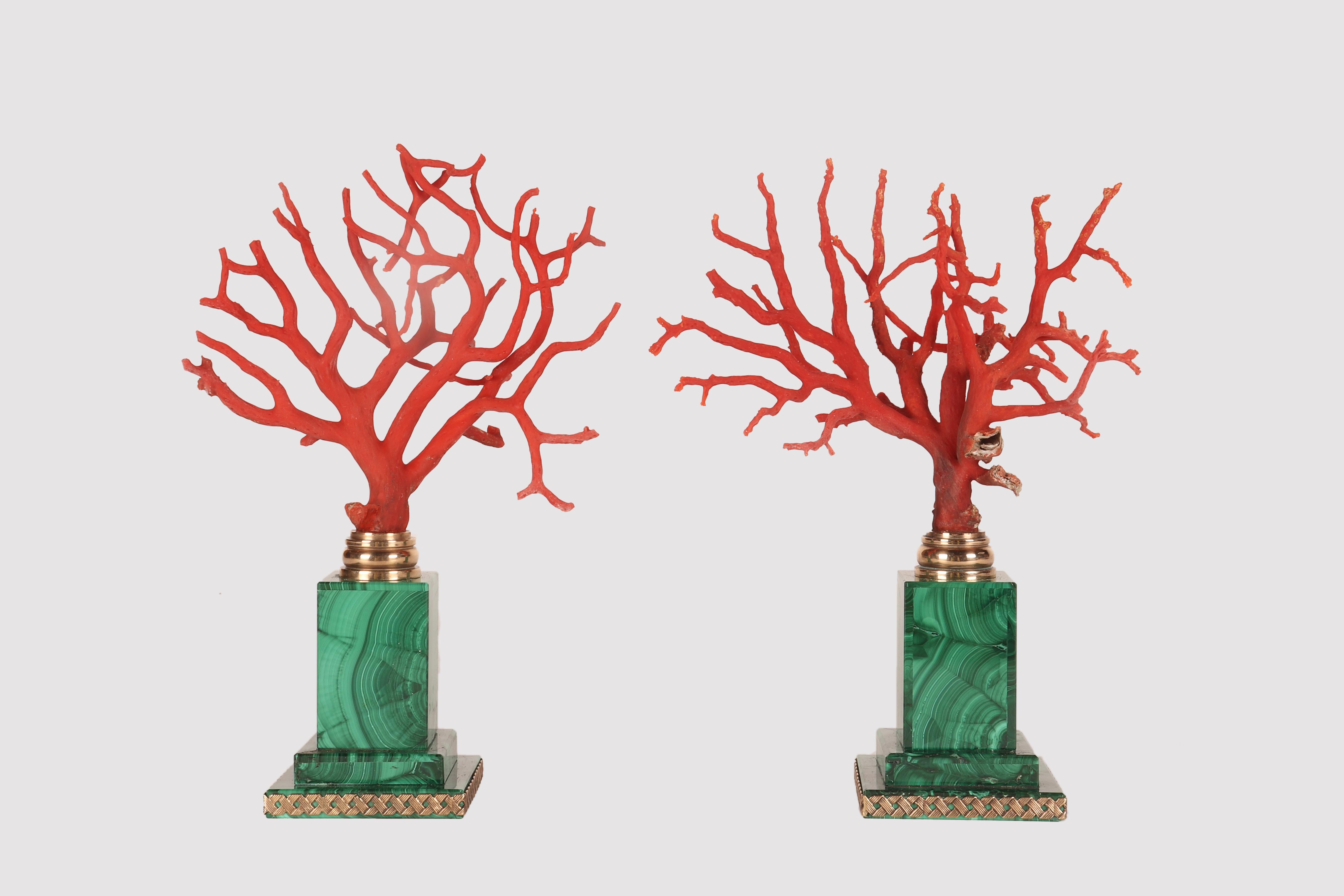 Pair of Mediterranean red coral branches (Corallium Rubrum), mounted on square-shaped marble bases, with a parallelepiped-shaped central body. The entire body is enriched by a mosaic of malachite slabs, with an intertwined bronze profile at the