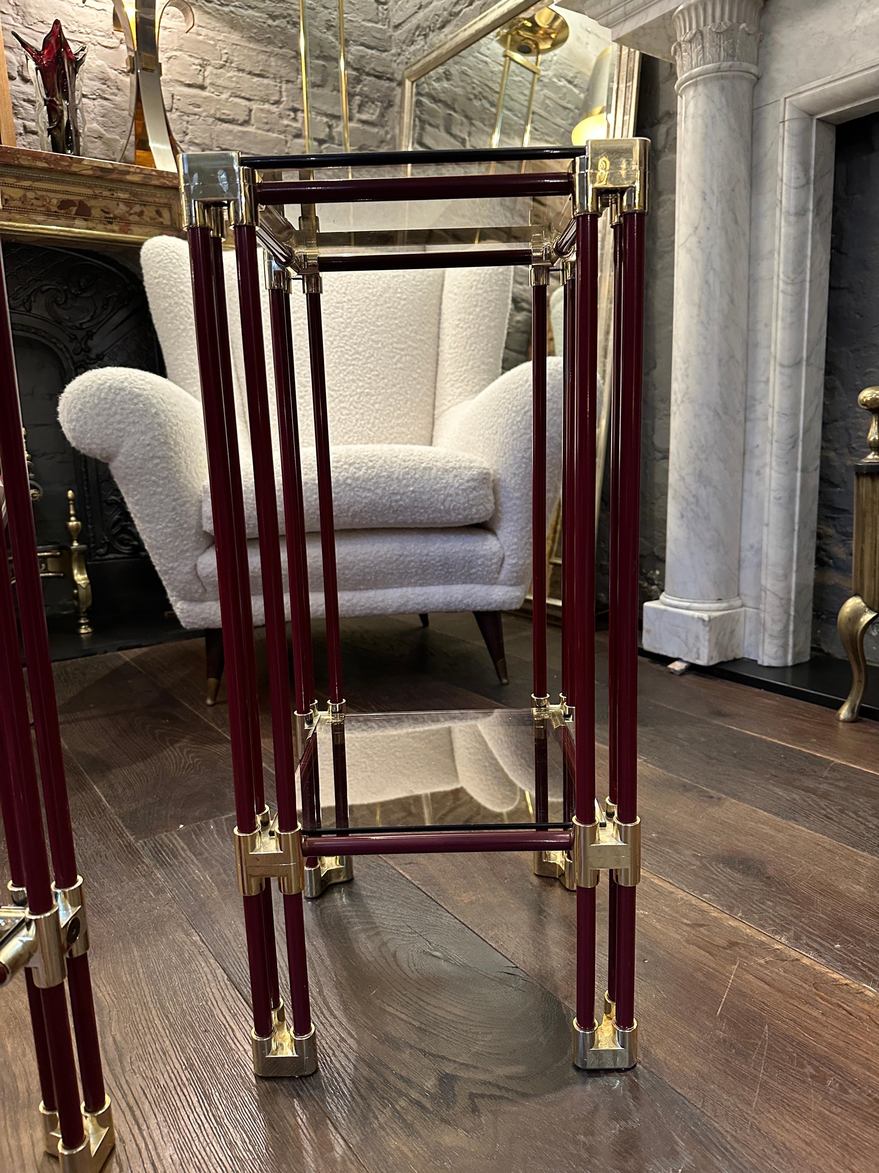 A pair of French tall two tier side or end tables, in lacquered burgundy or deep red colour with brass supports and accents. Original Smoked glass tops which are sunken into frames. 