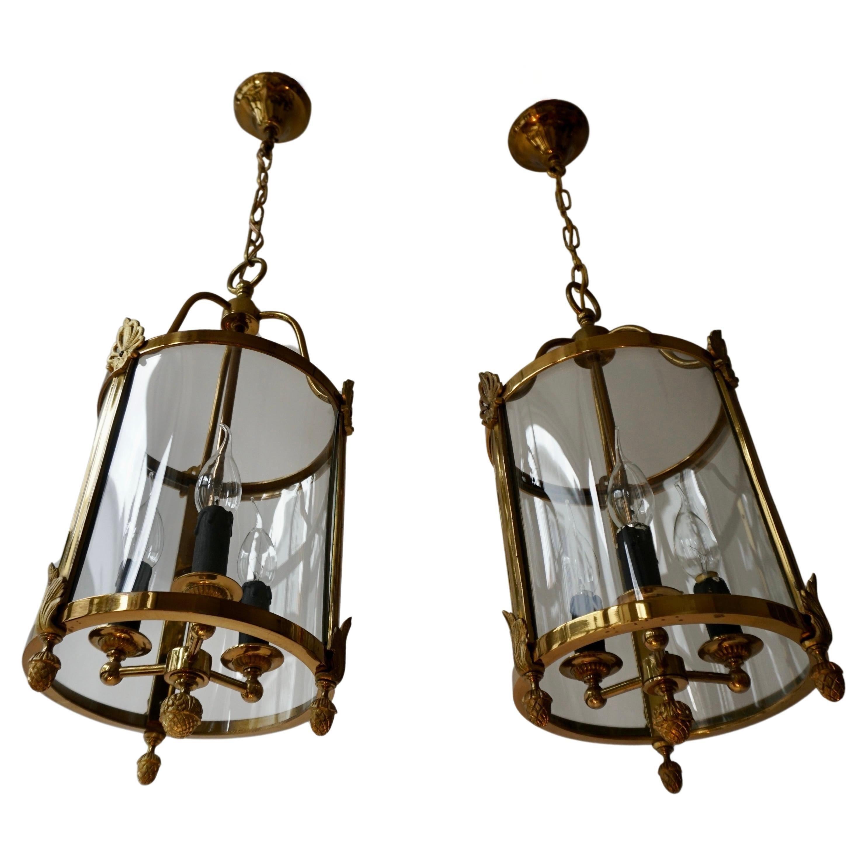 A petite French pair of brass lanterns with curved glass panels and decorated with pine cones and stylized.
In perfect working condition.
France.
First half of the 20th century

The lamp has three sockets for small incandescent lamps with screw base