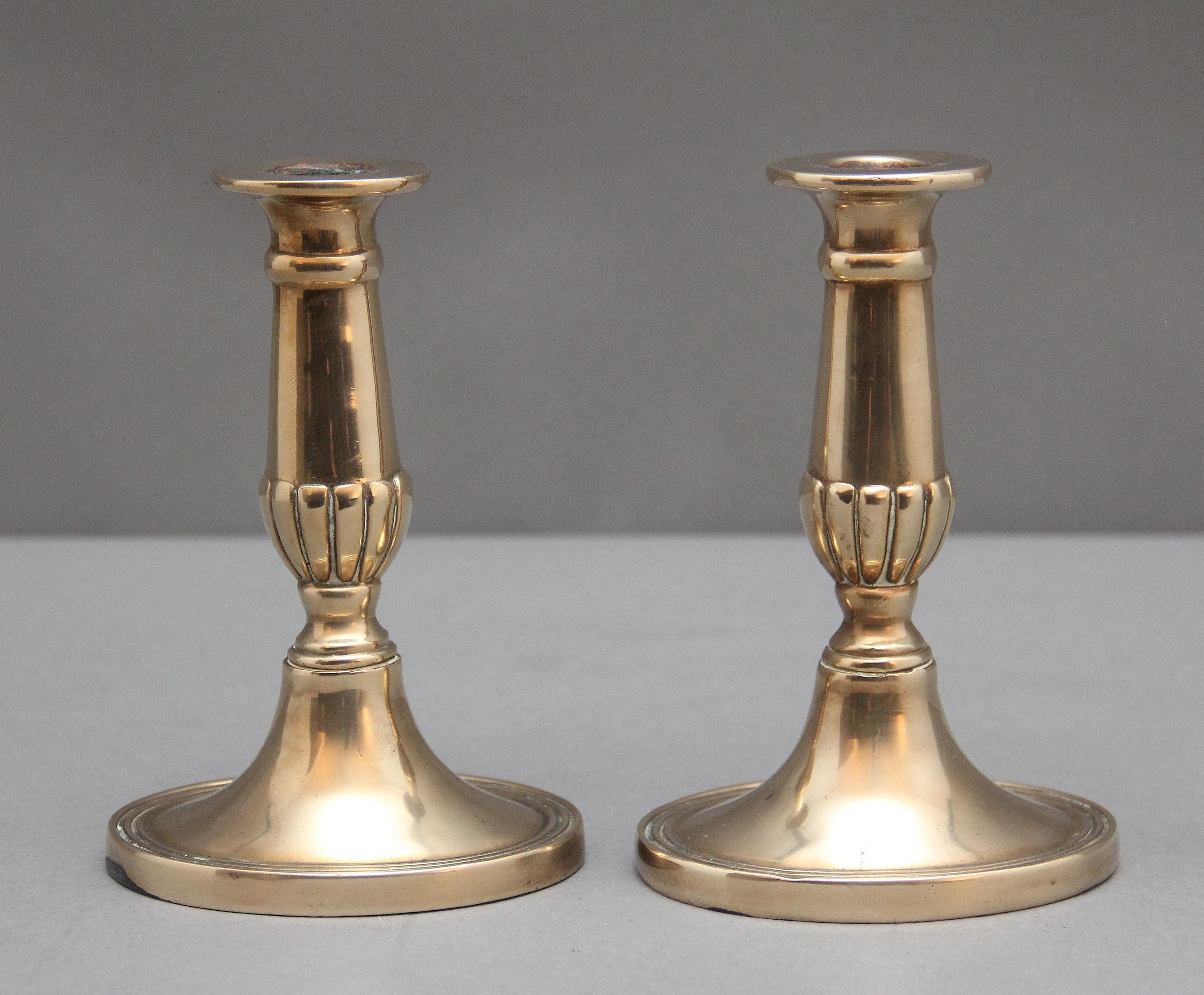 A fine pair of early 19th Century brass candlesticks, having elegant turned and reeded columns raised on an oval platform base reeded around the edge.  Circa 1800
